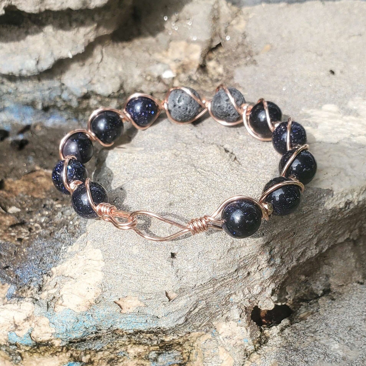 Copper Bracelet with black beads and rose gold accents on a stone surface