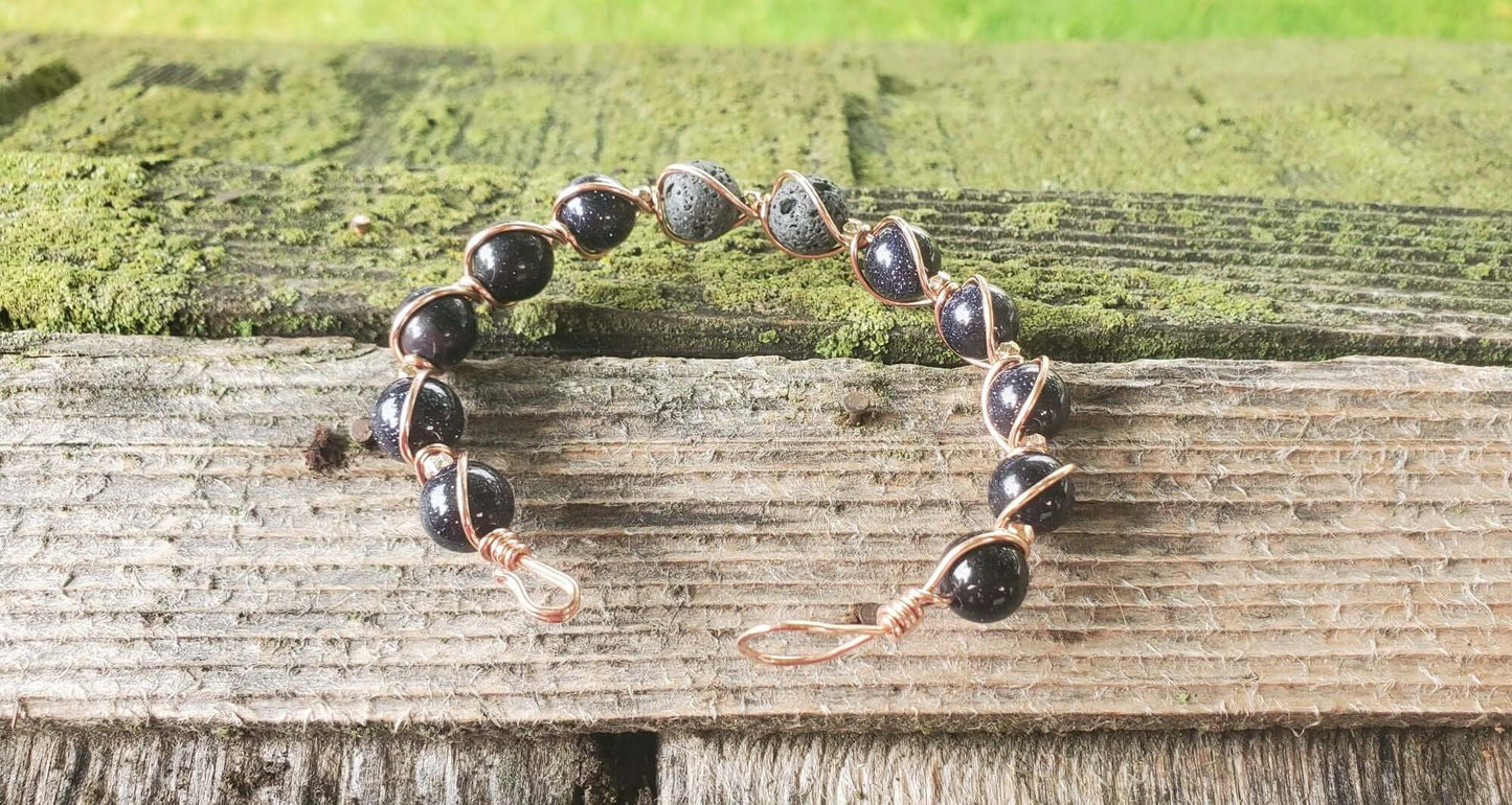 Bracelet with black beads and gold accents on a wooden surface