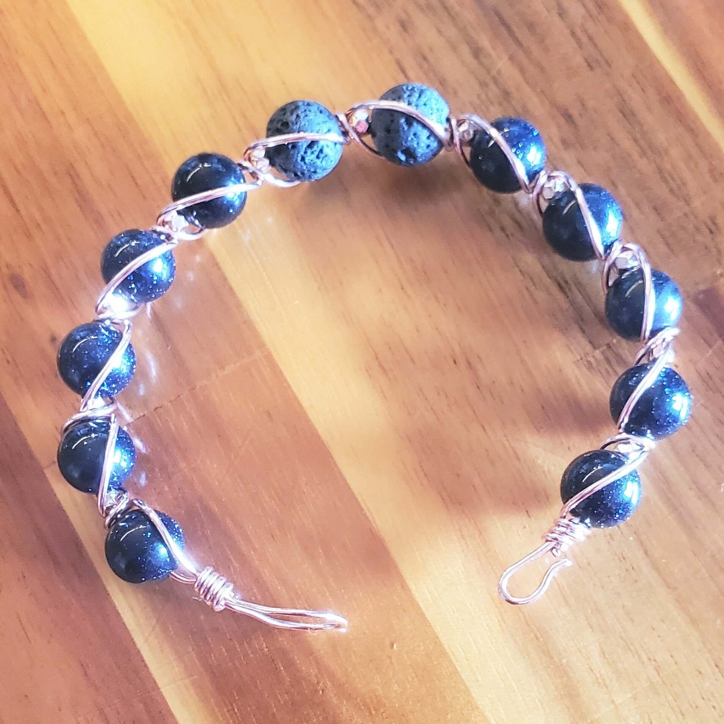Beaded bracelet with blue beads and silver wire on a wooden surface