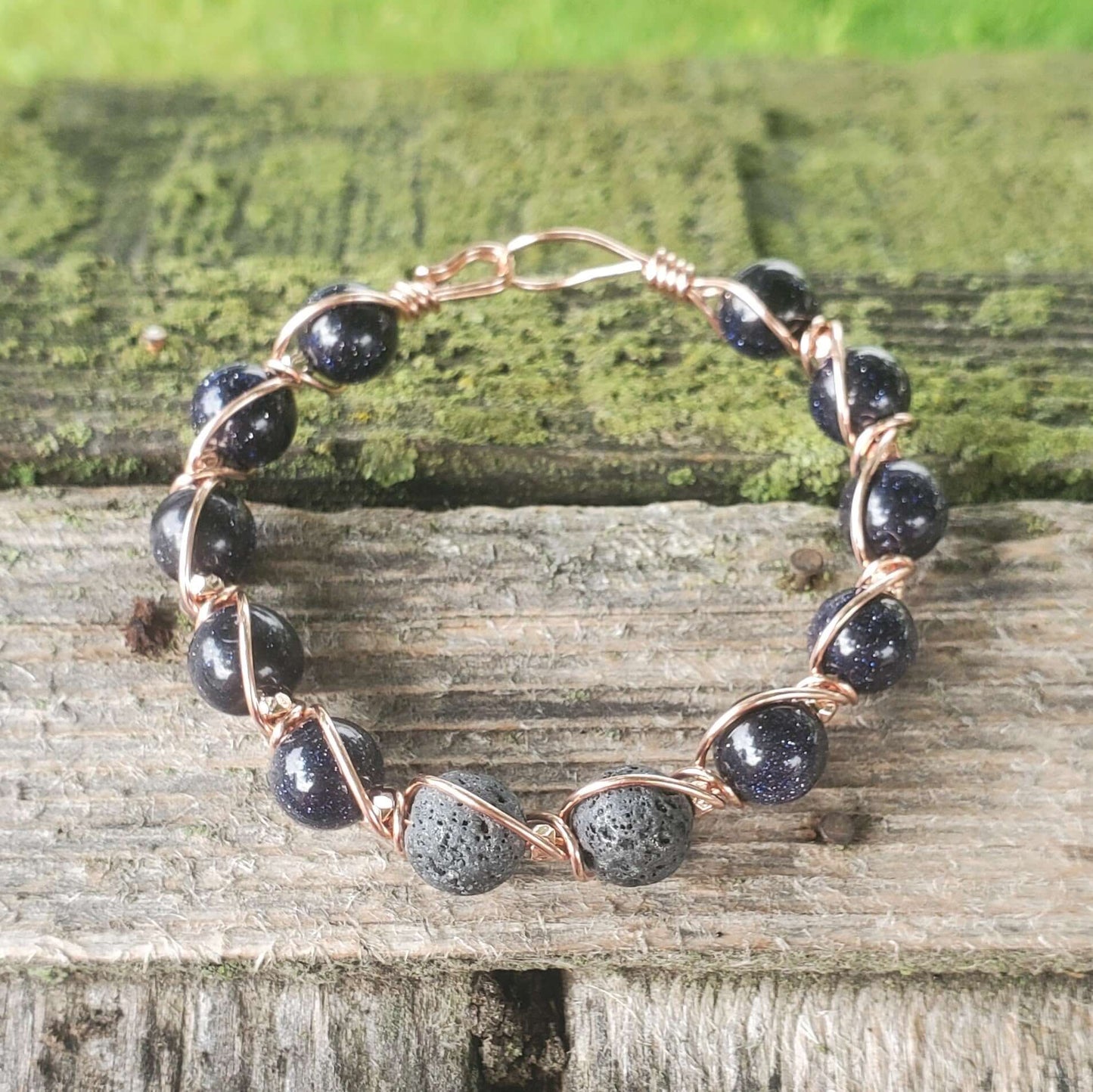 Bracelet with black beads and rose gold wire on a wooden surface
