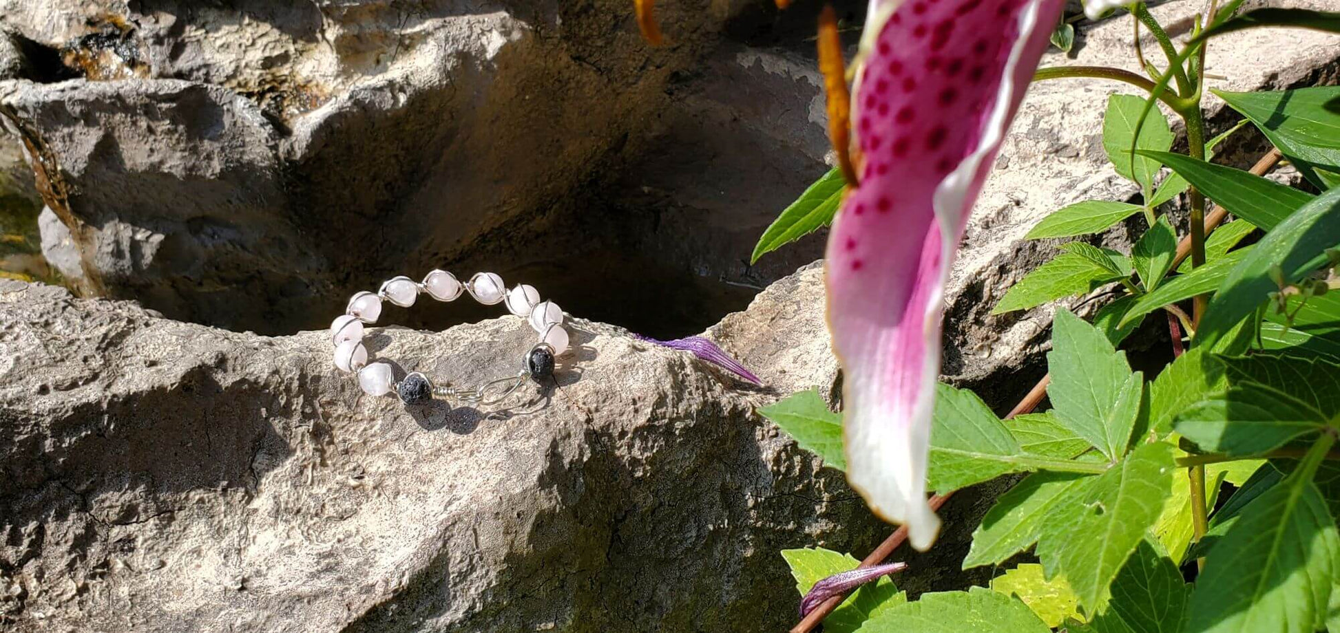 Bracelet on a rock with a flower and leaves in the background