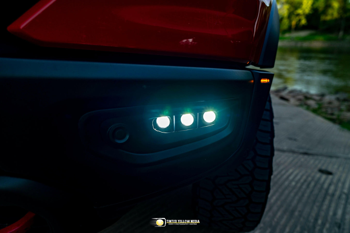 Close-up of a vehicle's fog light with illuminated LED lights on a dark background.