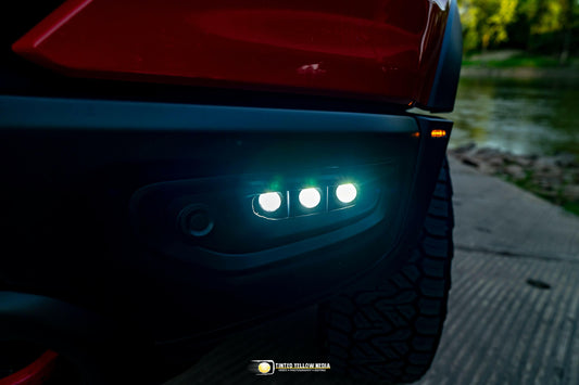 Close-up of a vehicle's fog light with illuminated LED lights on a dark background.