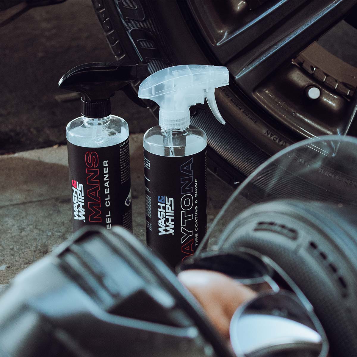 Two bottles of car cleaning products on a car seat with a person's hand holding a mirror.