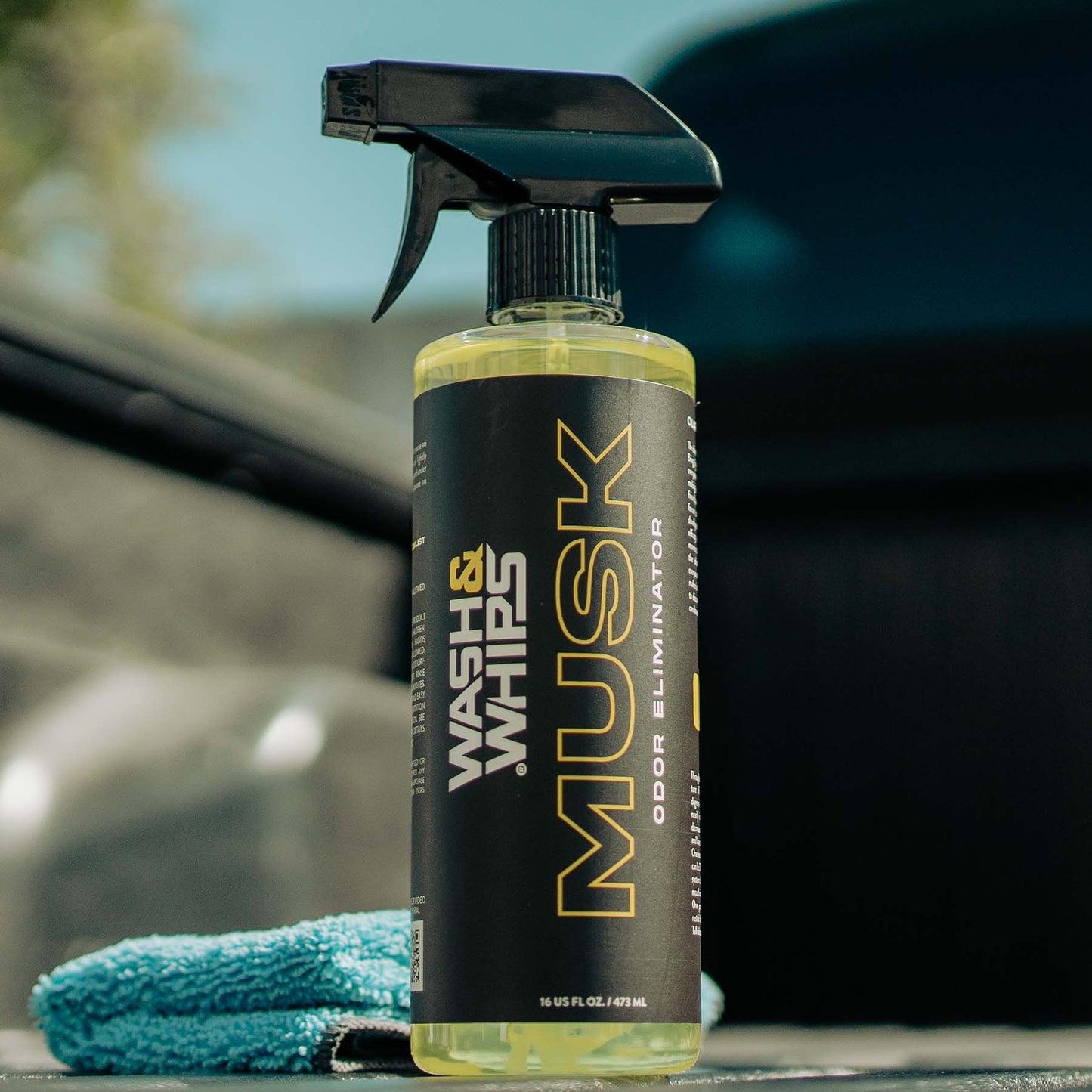 Spray bottle labeled 'Wash & Whips Musk' with a car in the background
