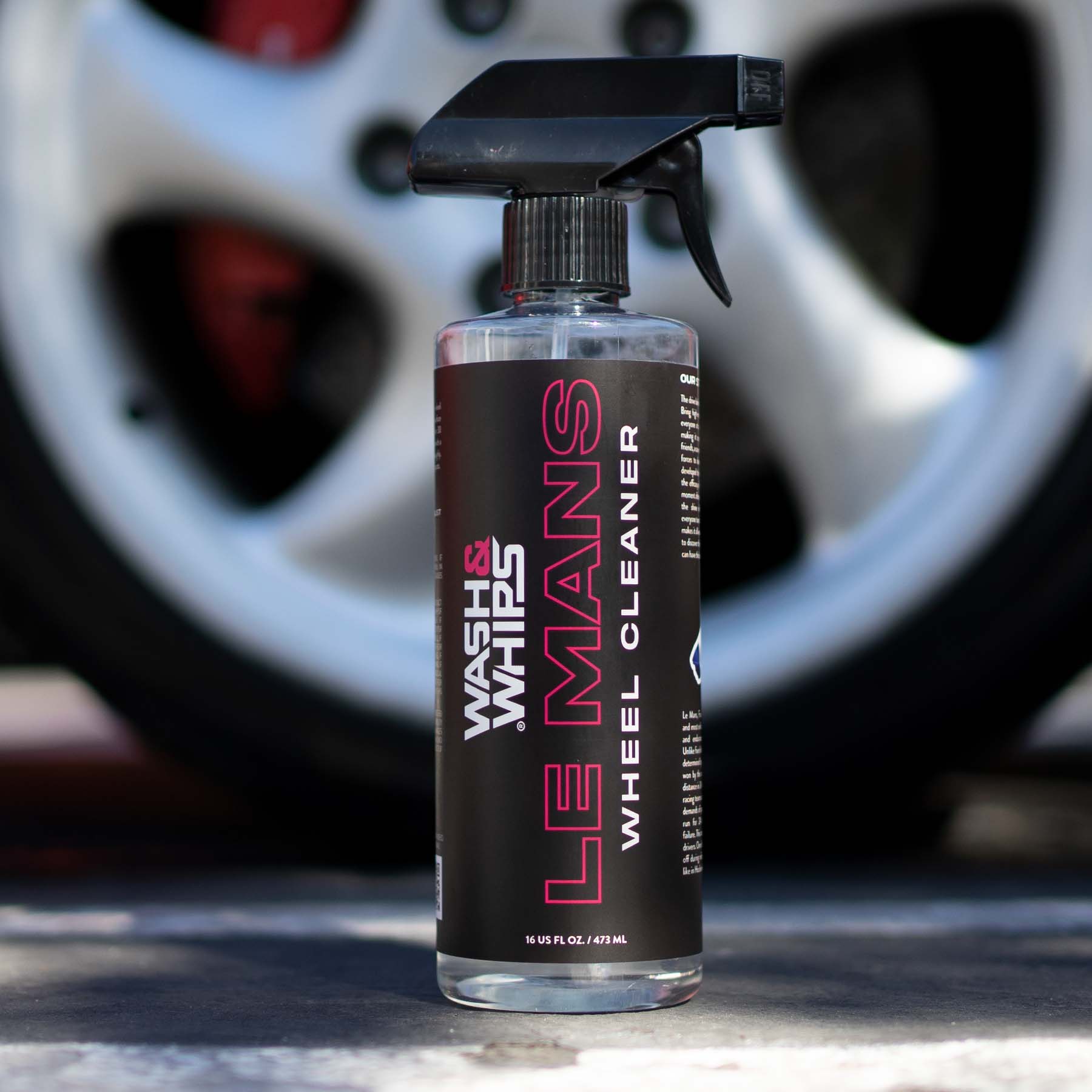 Wheel cleaner spray bottle with a car wheel in the background