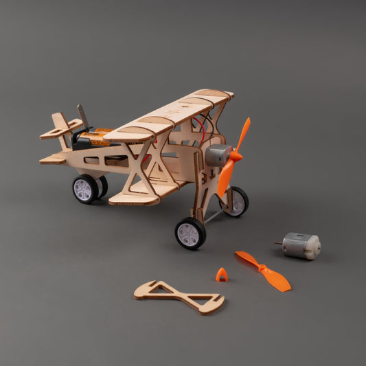 Wooden toy airplane model with tools and parts on a gray background