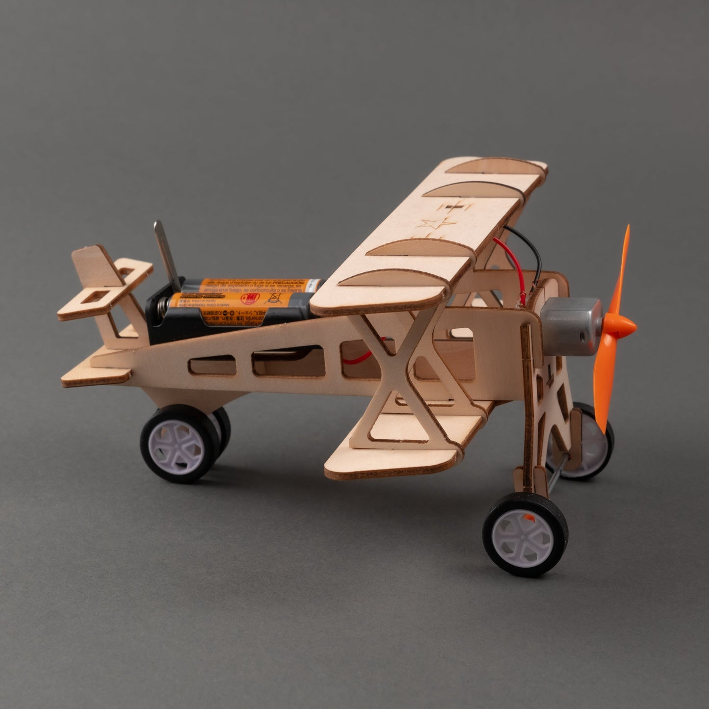 Wooden model airplane with wheels and an orange propeller on a gray background