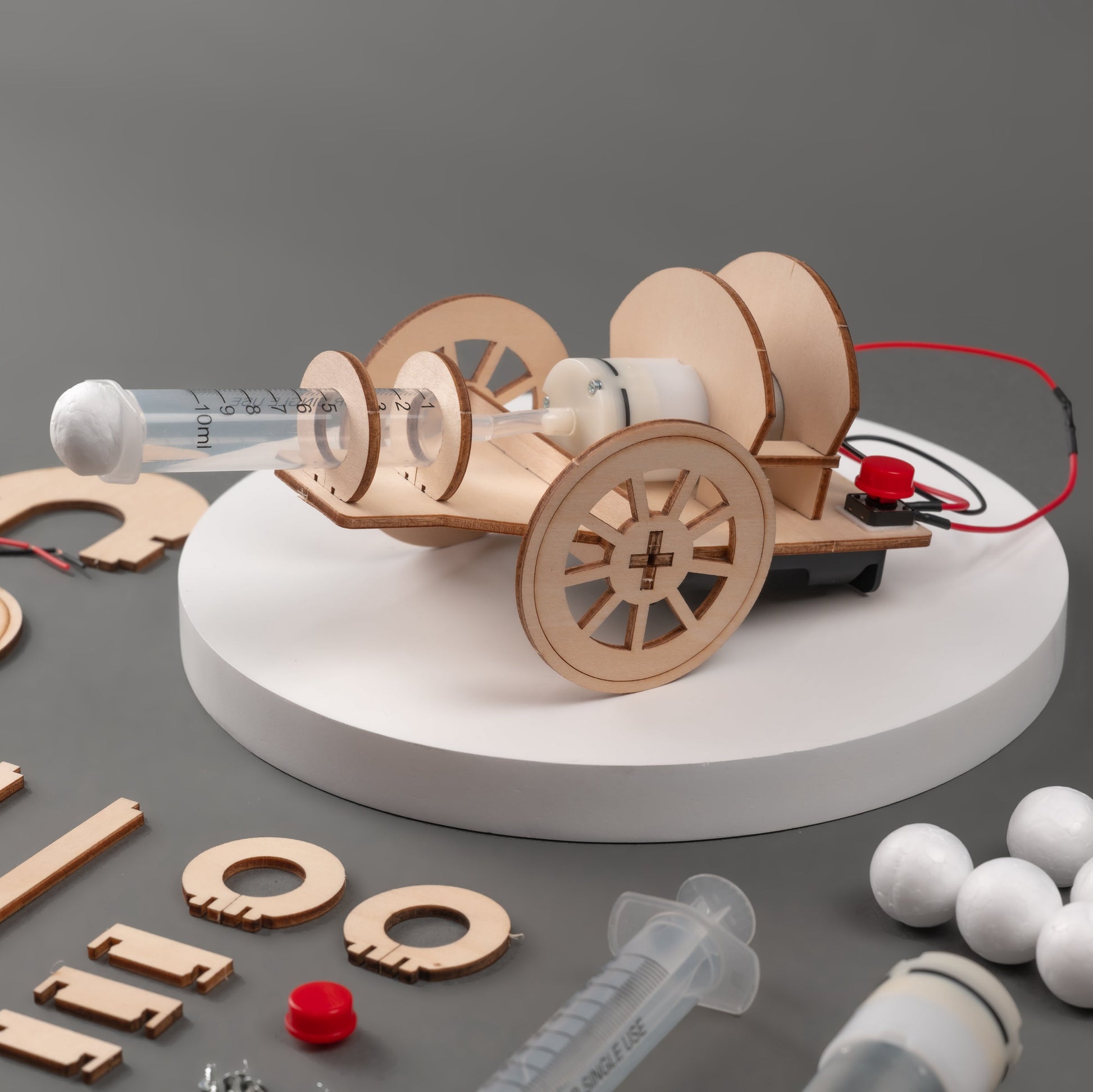 Wooden model of a vehicle with wheels and syringes on a gray background