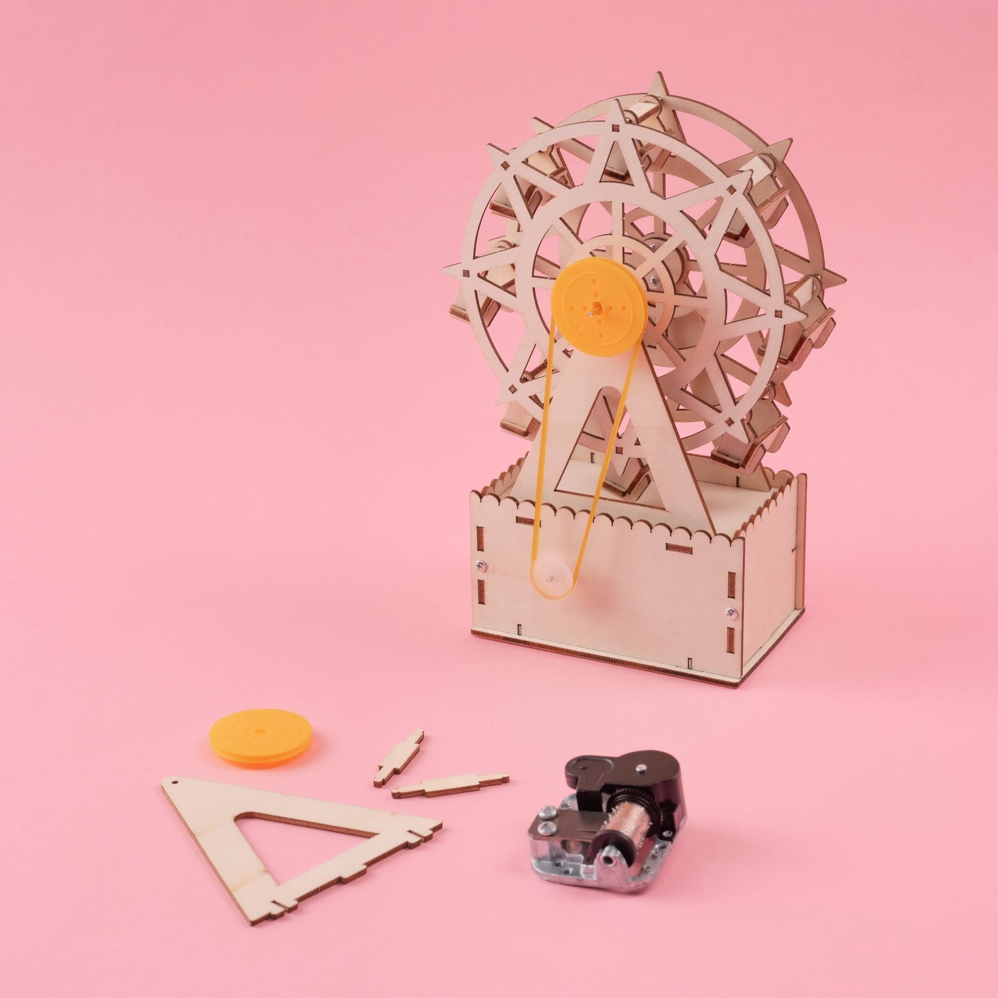 Wooden mechanical model kit with gears on a pink background