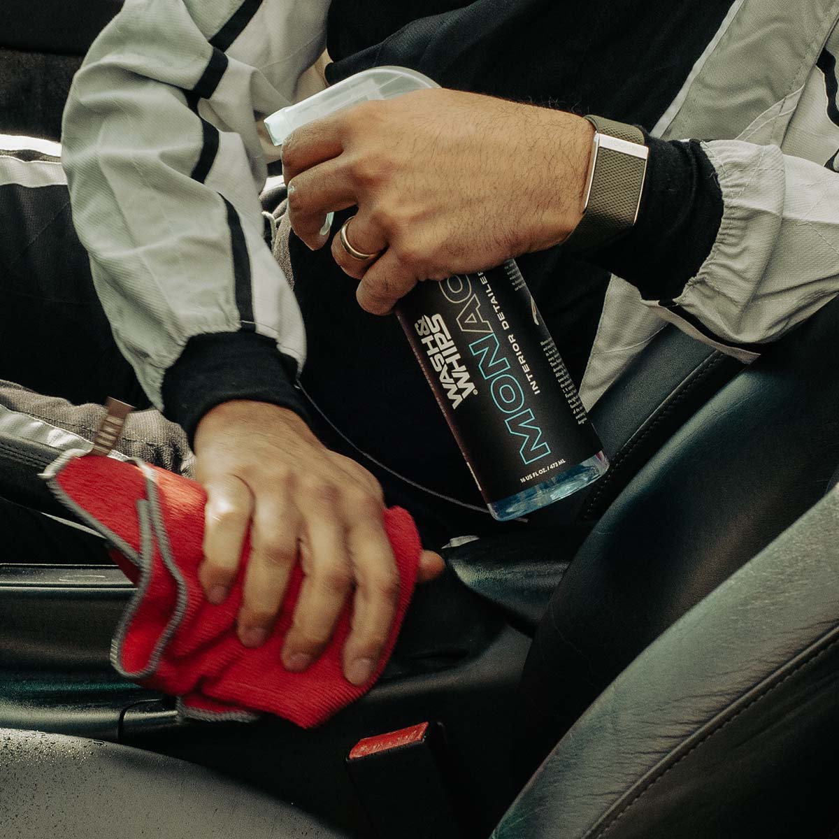 Person cleaning car interior with a red cloth and MONACO product
