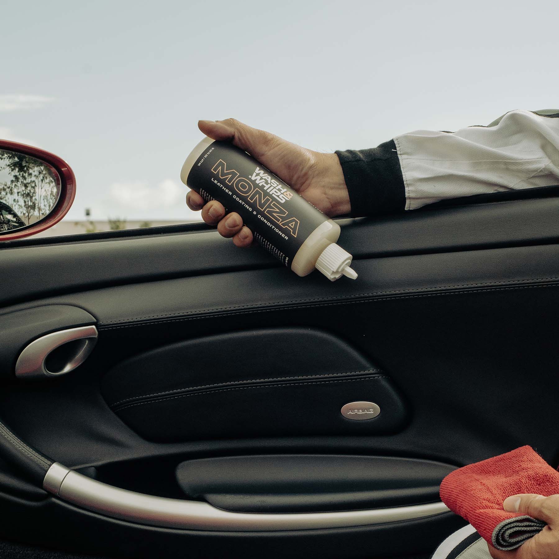Person applying a product to a car's interior with a can labeled 'Monza'.