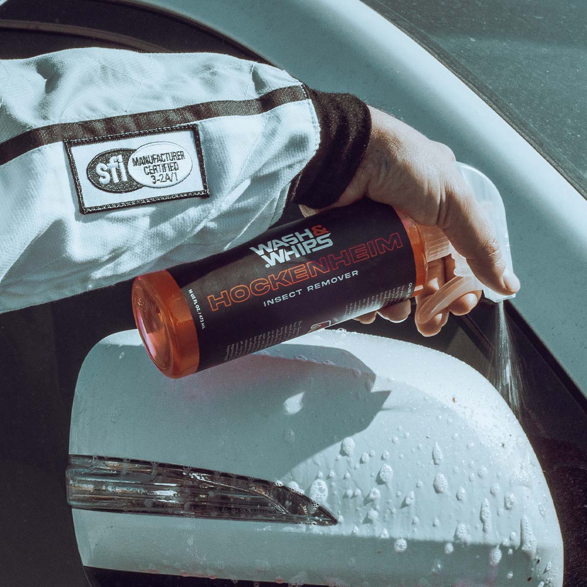 Person holding a can of Hockenheim insect remover next to a car