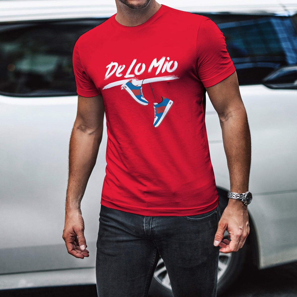 Person wearing a red t-shirt with 'DeLo Mio' logo in front of a white car.