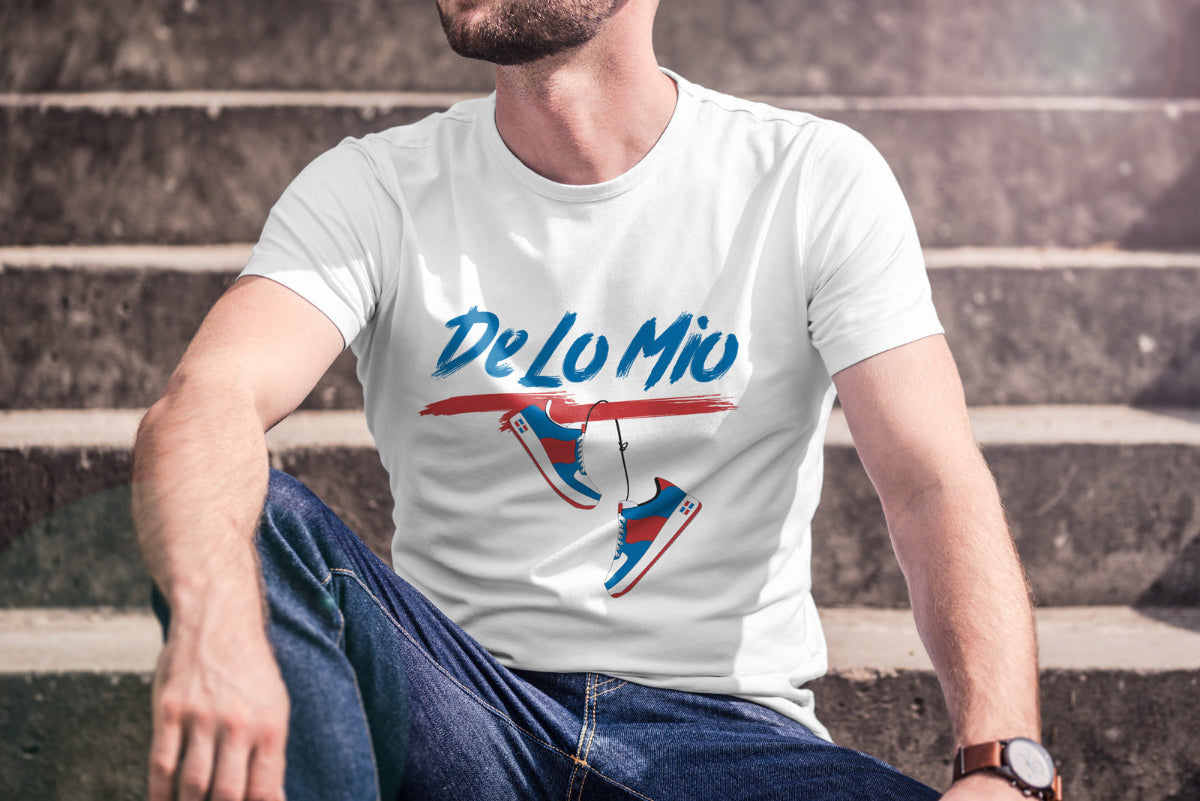 Person wearing a white t-shirt with 'De Lo Mio' design sitting on steps.