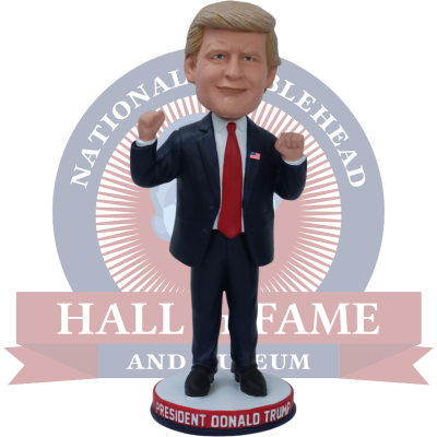 Trump Bobblehead figure standing in front of a 'National Bobblehead Hall of Fame and Museum' logo.