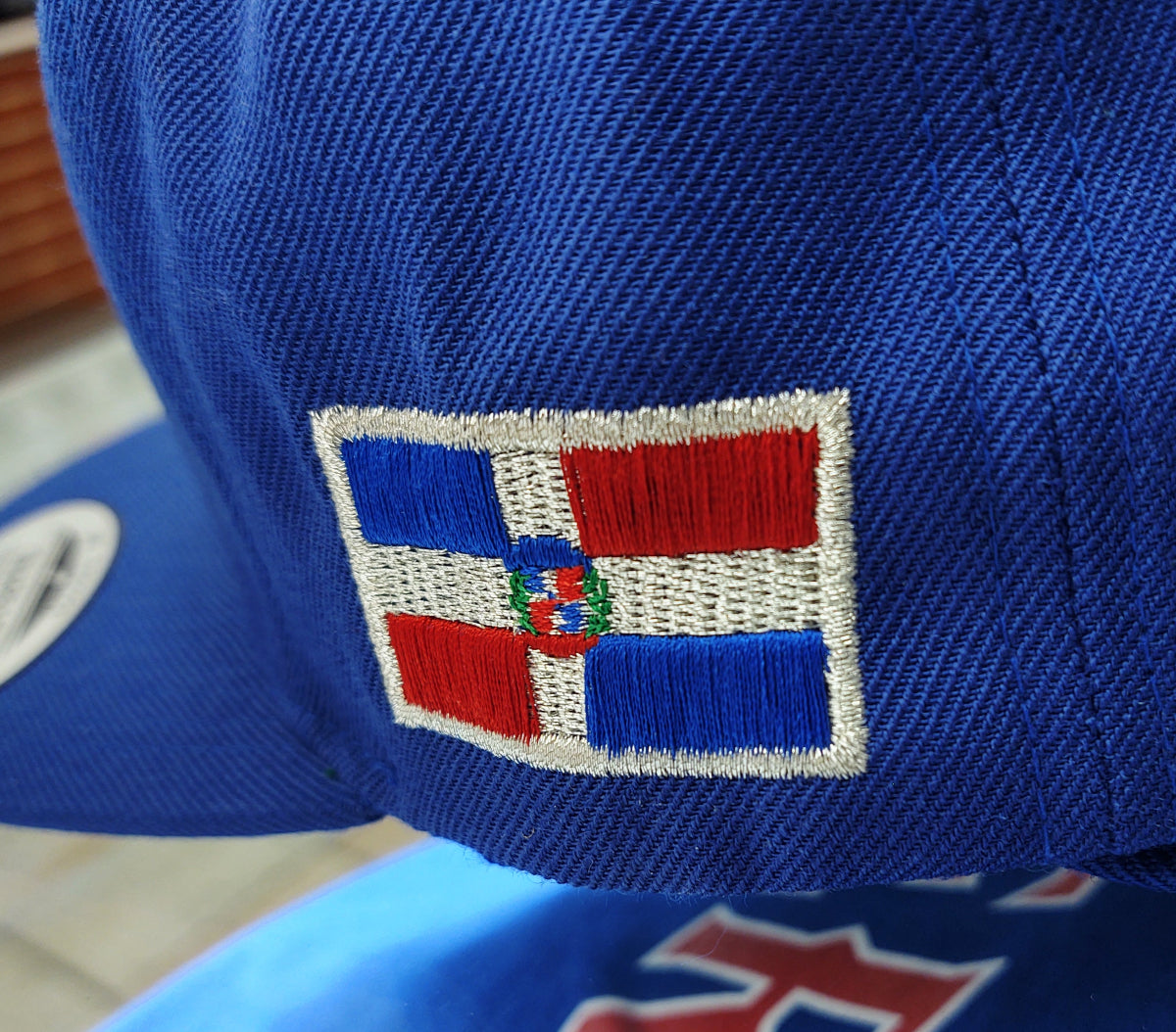 Close-up of a blue cap with a red, white, and blue Dominican Flag on a blurred background