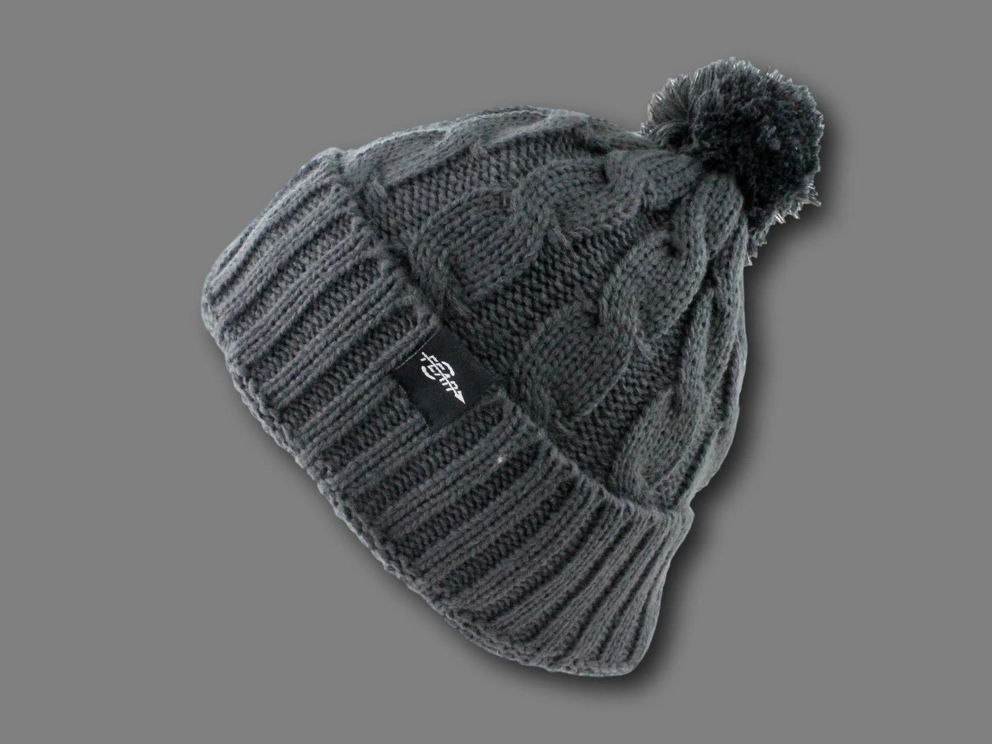 Knitted beanie with pom-pom on a gray background