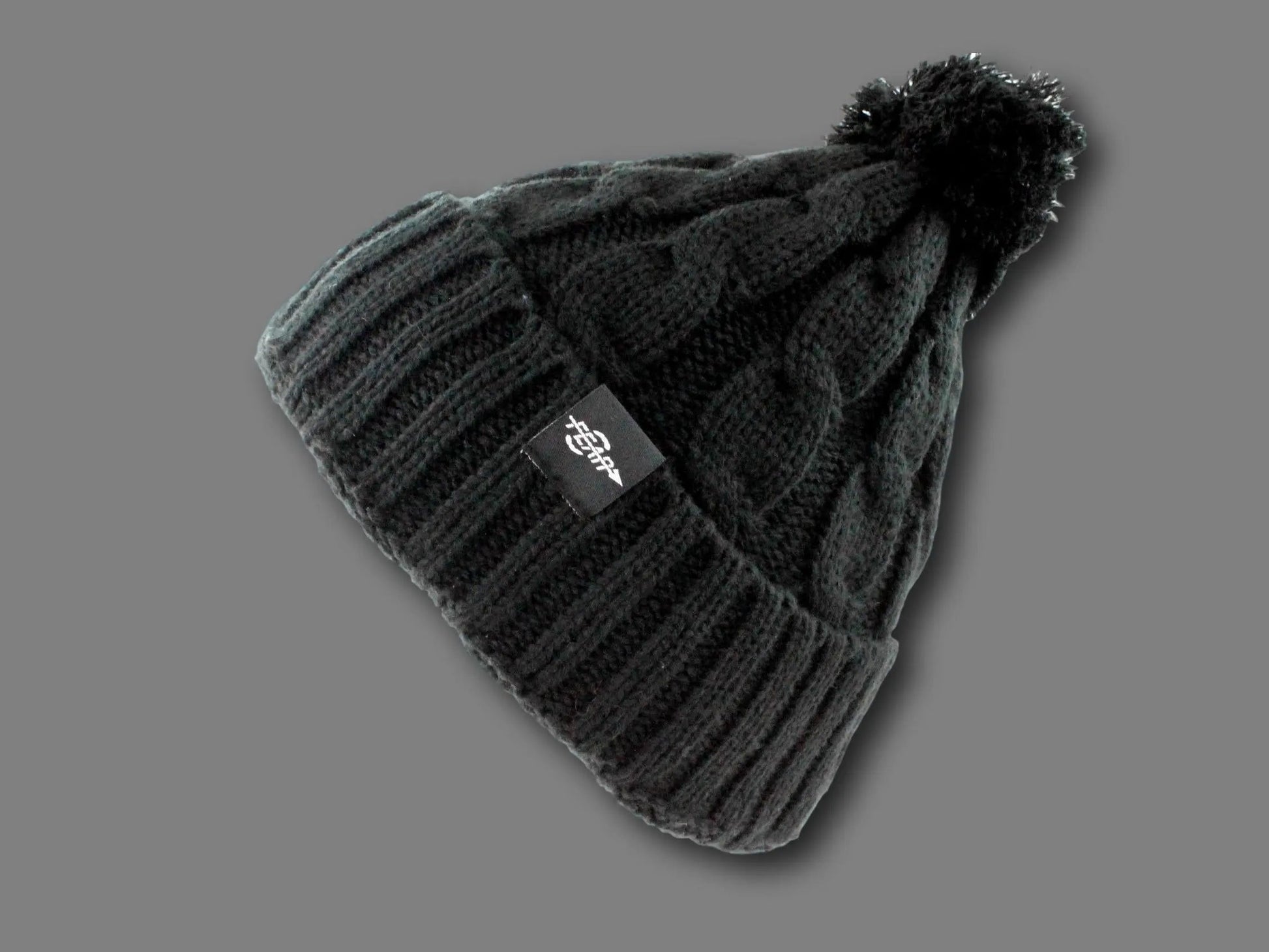 Knit beanie with pom-pom on a light gray background
