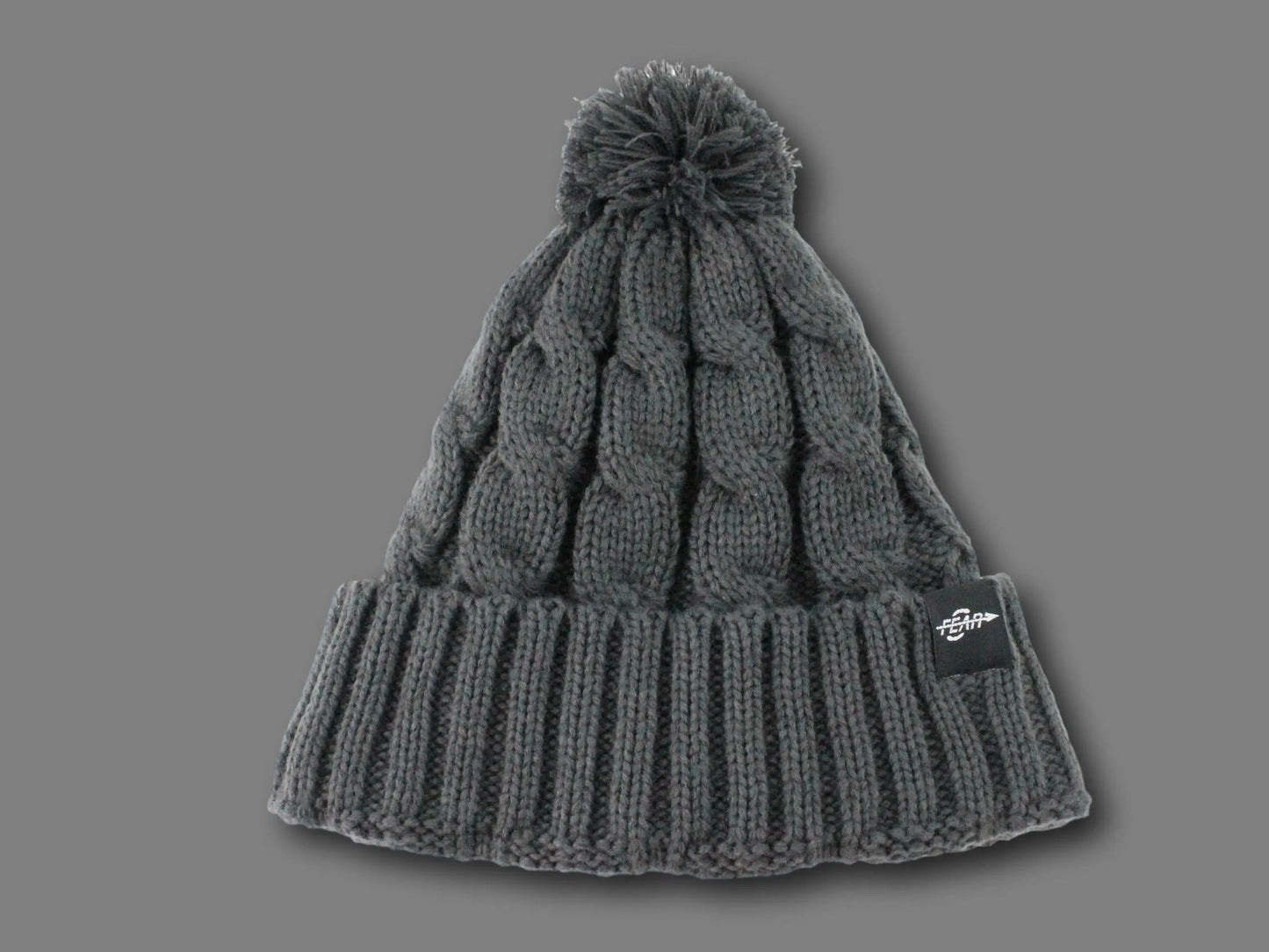 Gray knit beanie with pom-pom on a gray background