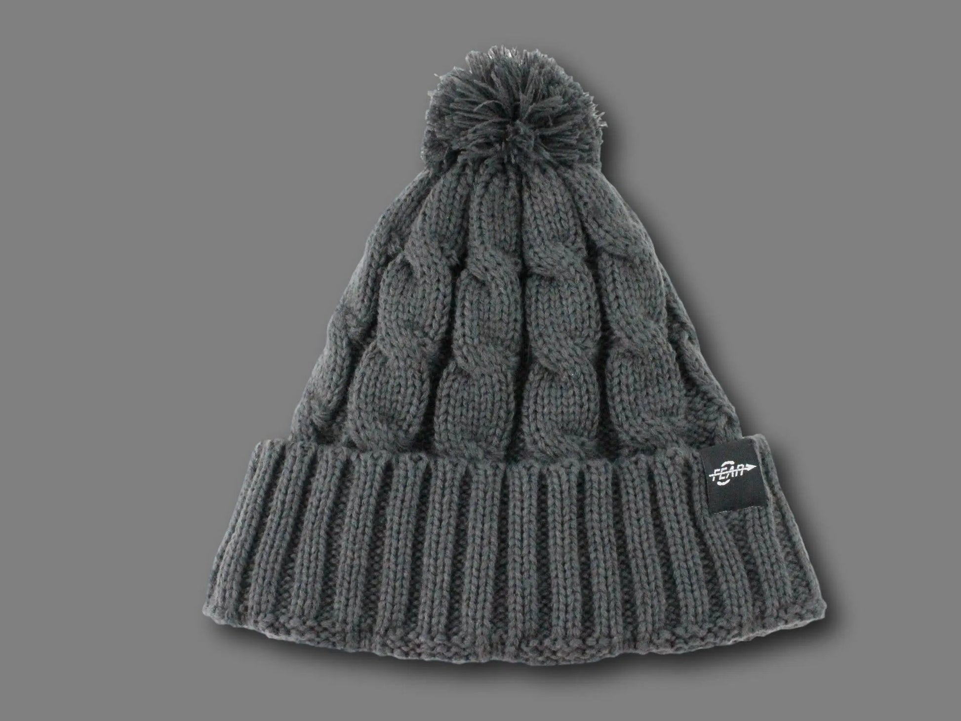Gray knit beanie with pom-pom on a gray background
