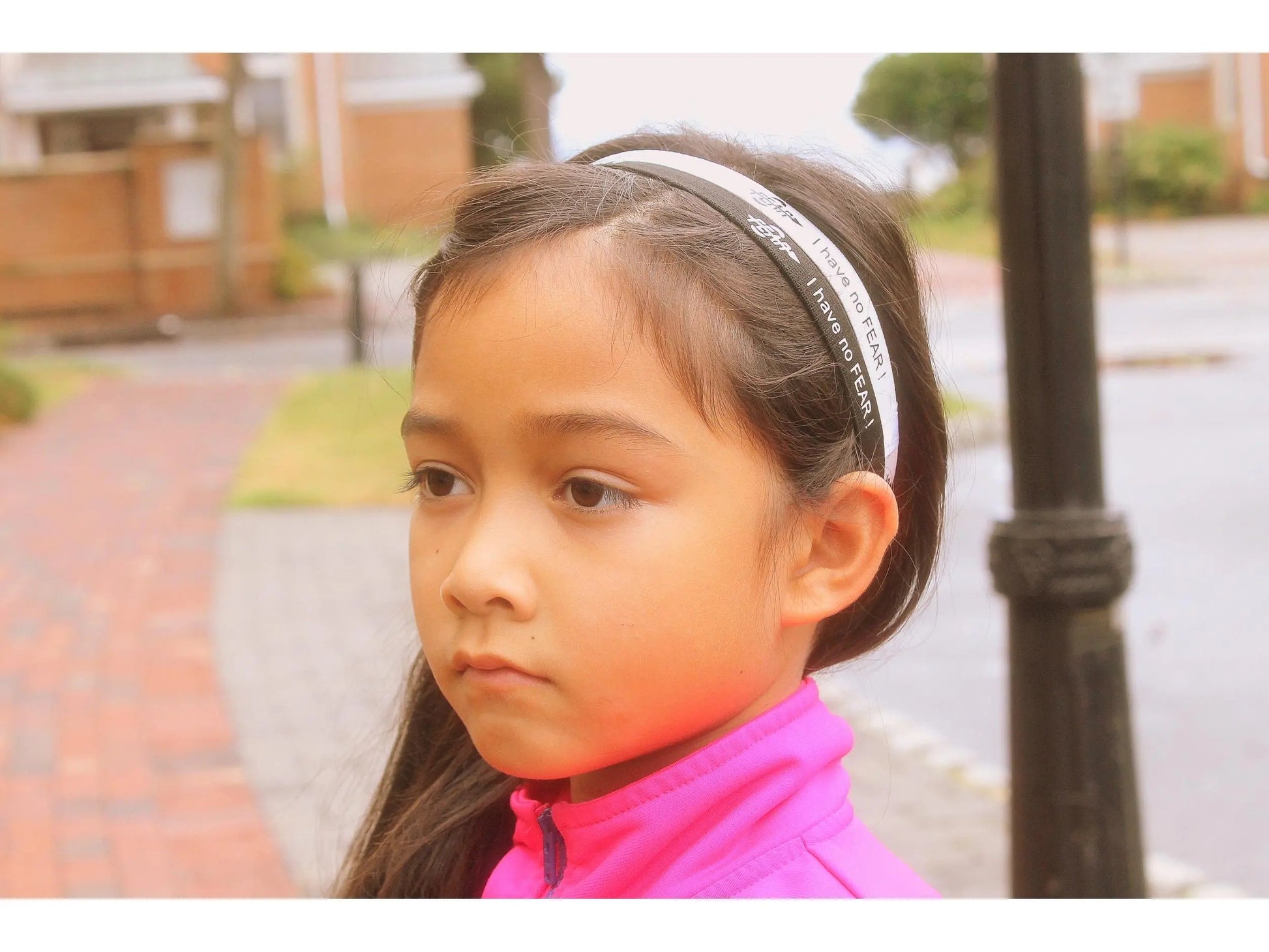 Young girl with a headband looking off to the side, with a blurred background