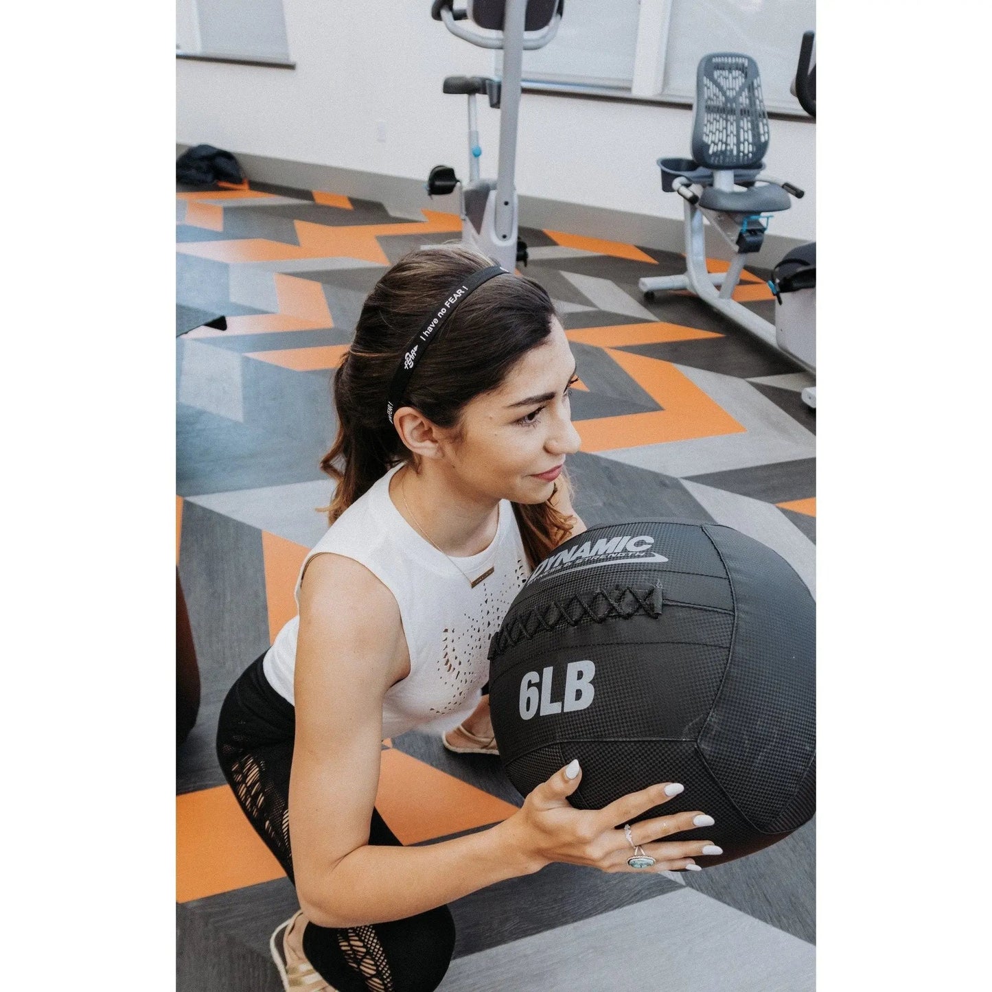 Woman holding a black medicine ball wearing a fear0 headband