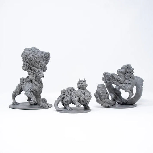 Three gray fantasy creature figurines on a white background