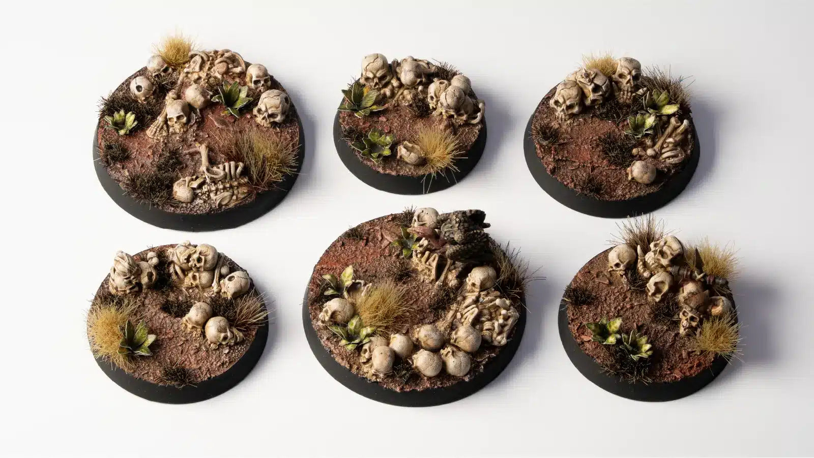 Six round miniature bases with detailed scenery on a white background
