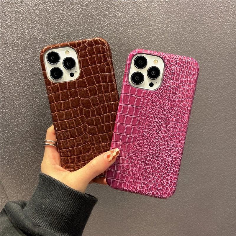 Two phone cases, one brown and one pink, held against a gray background.