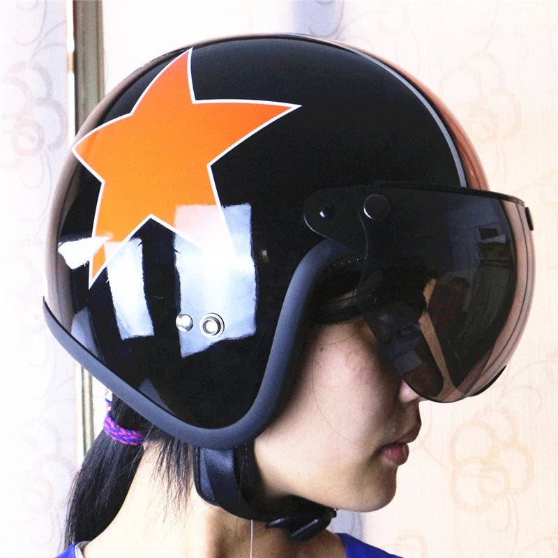 Person wearing a black helmet with an orange star design and visor.