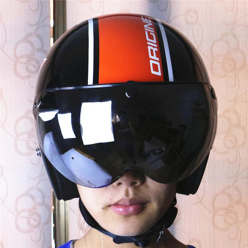 Person wearing a black and orange helmet with 'ORIGINE' branding and visors.