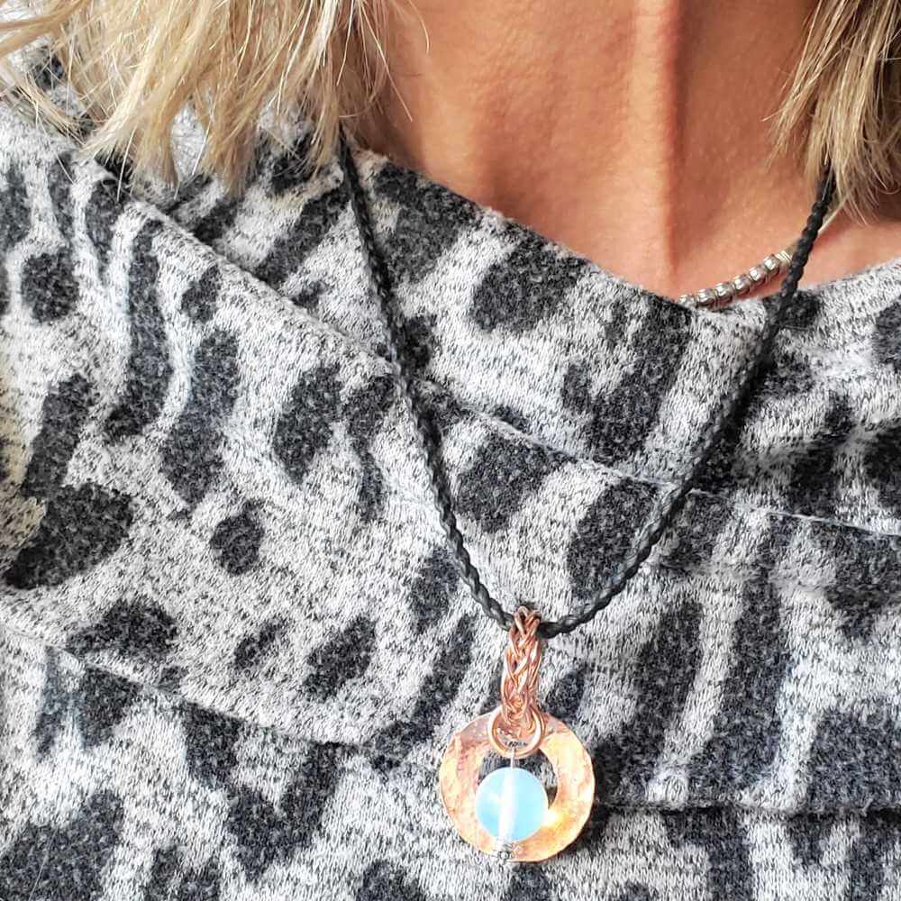 Necklace with a pendant worn by a person in a patterned outfit