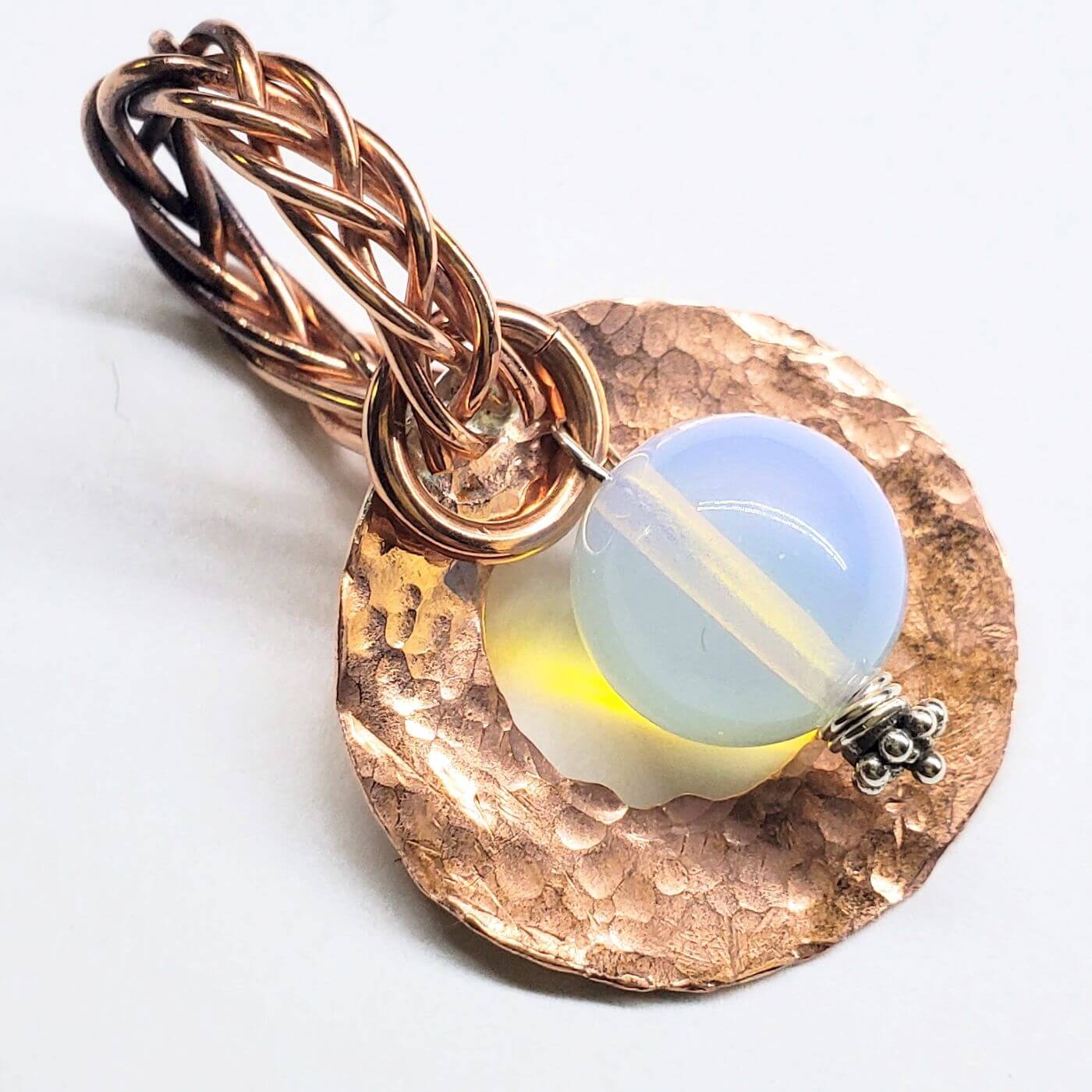 Copper pendant with a blue and yellow glass bead on a white background
