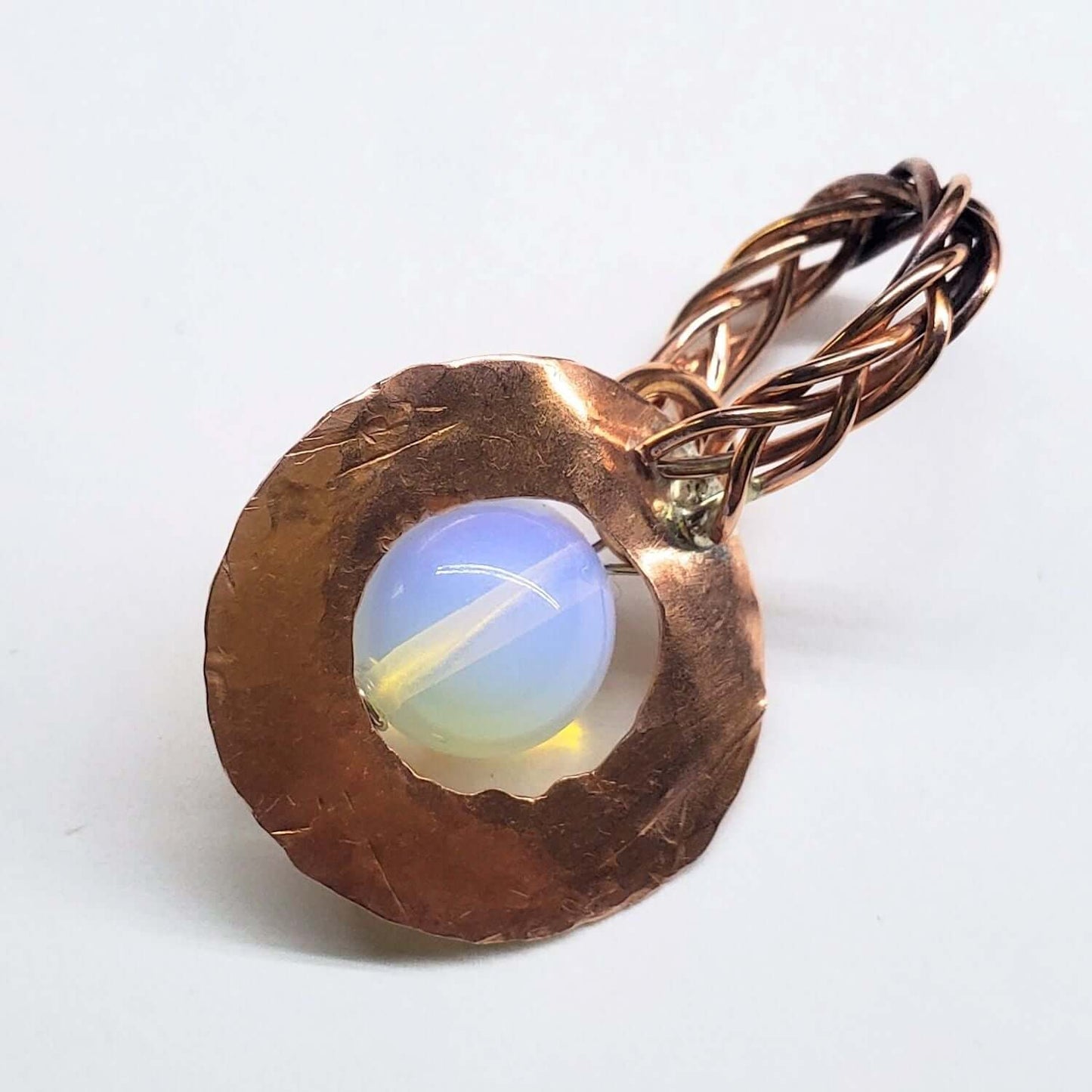 Copper tone pendant with a central opal stone on a white background