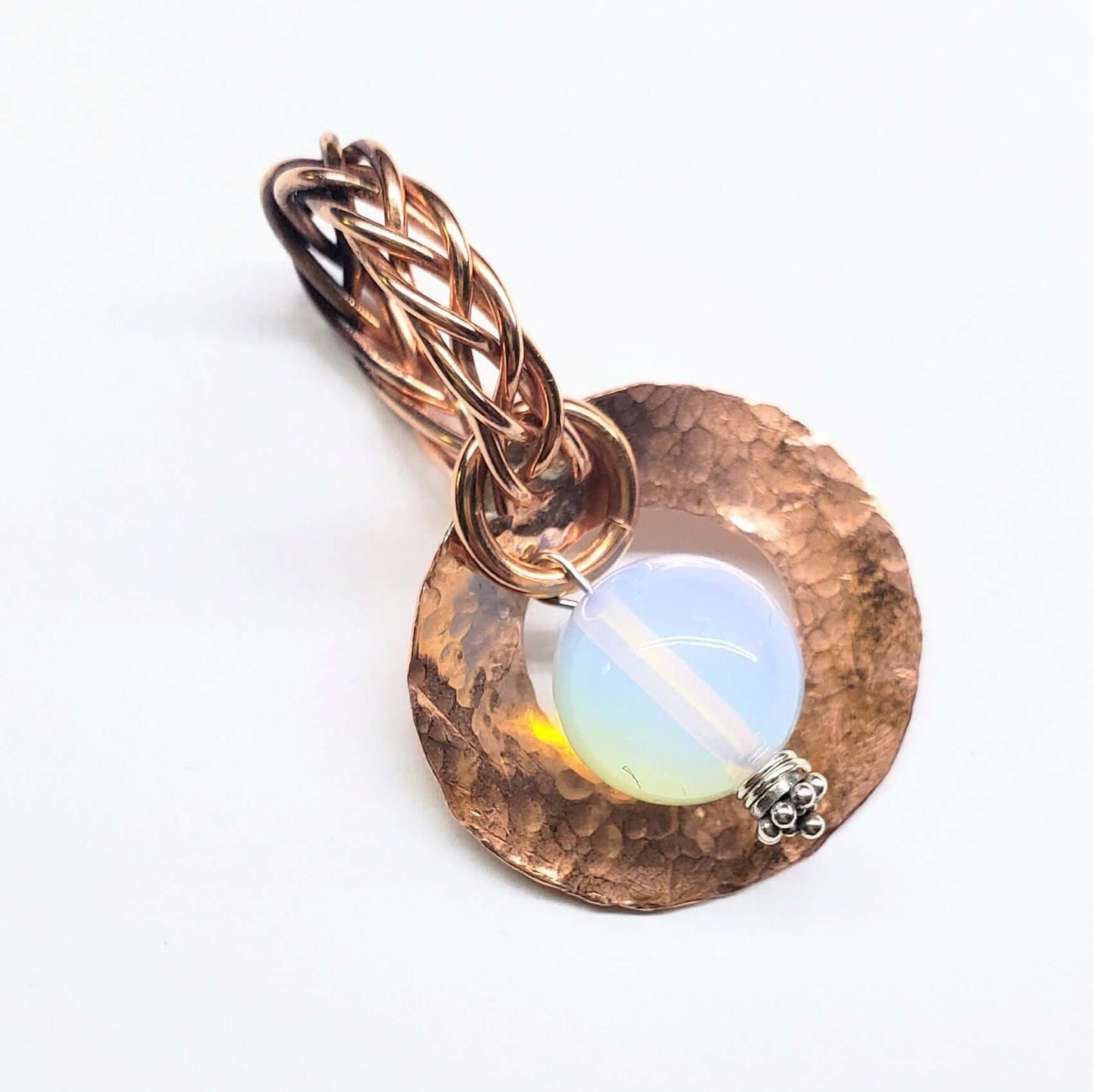 Copper colored pendant with a  gemstone on a white background