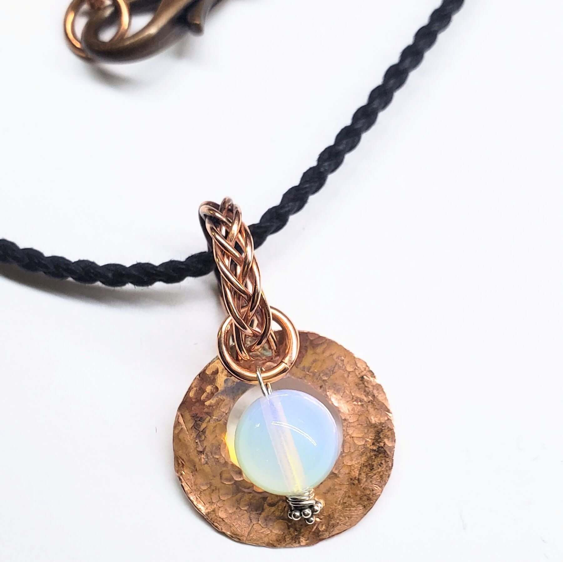 Necklace with a copper pendant featuring an opal stone on a white background