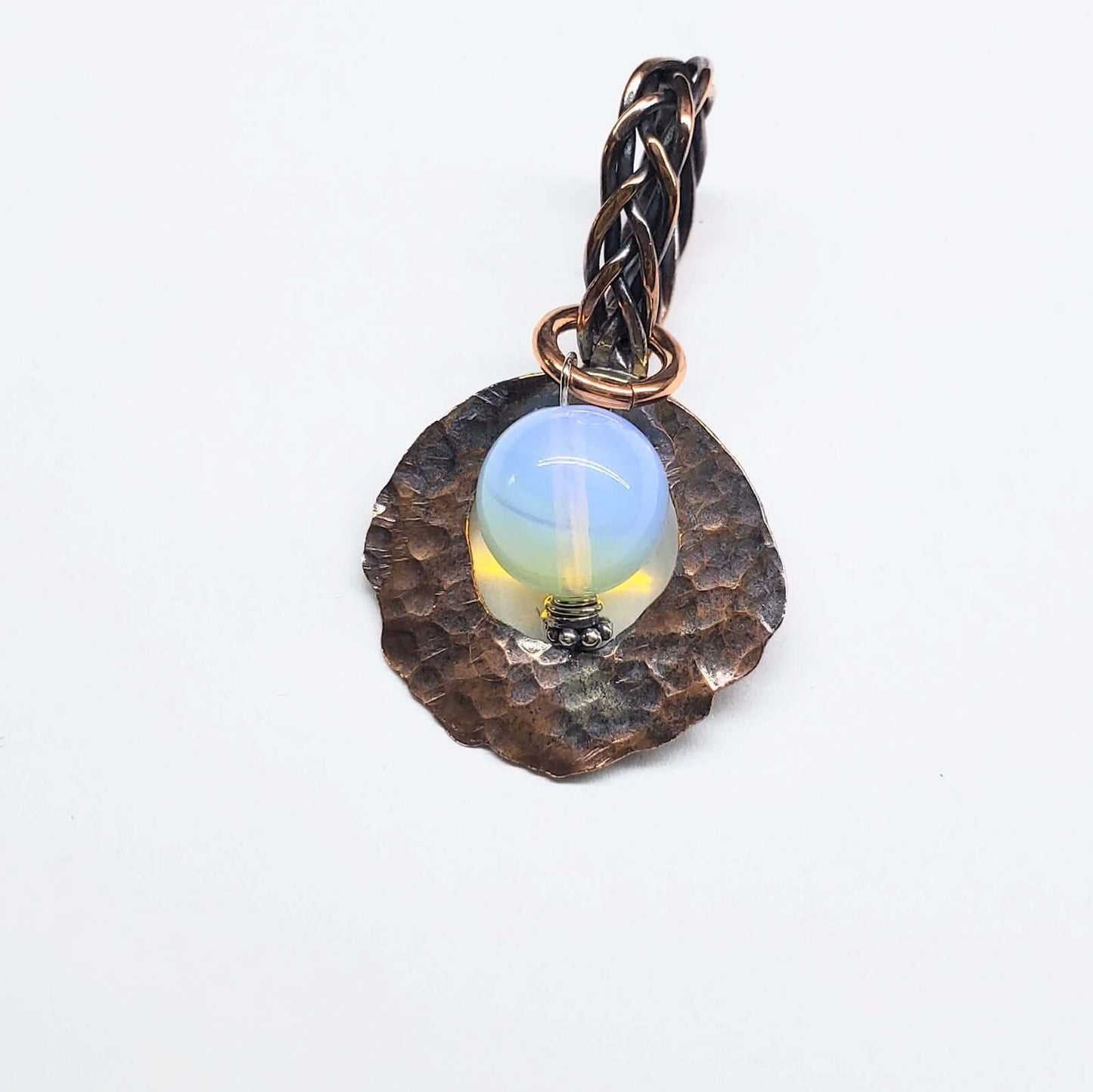 Jewelry pendant with a blue stone and braided design on a white background