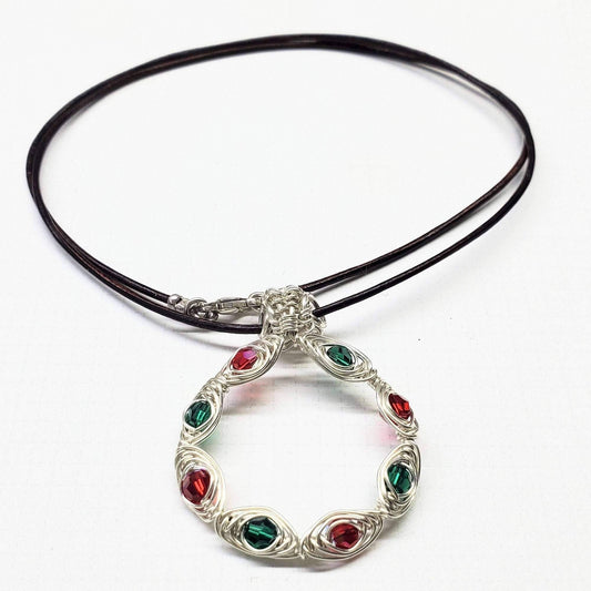 Necklace with a silver circular pendant featuring red and green gemstones on a white background