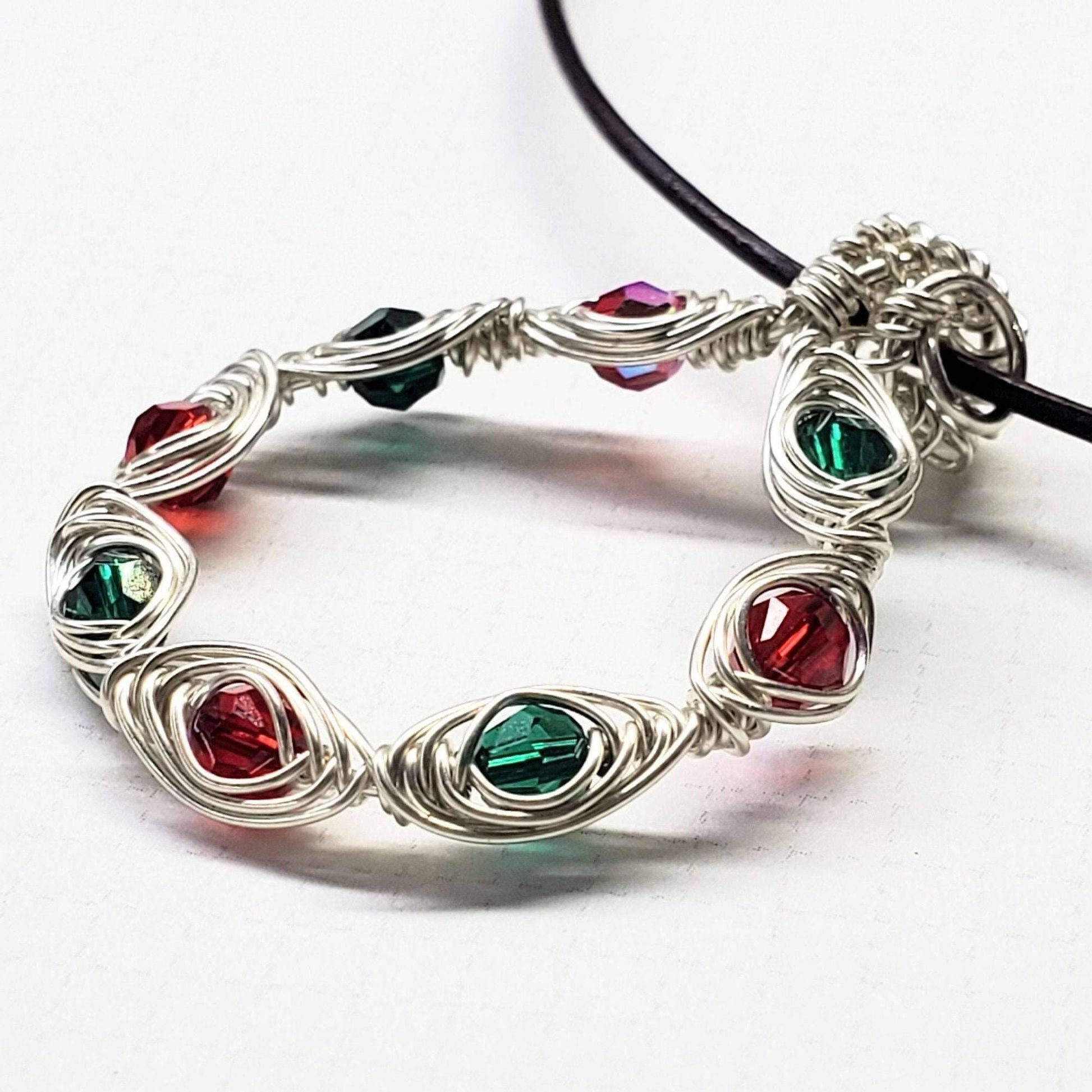 Silver bracelet with red and green gemstones on a white background