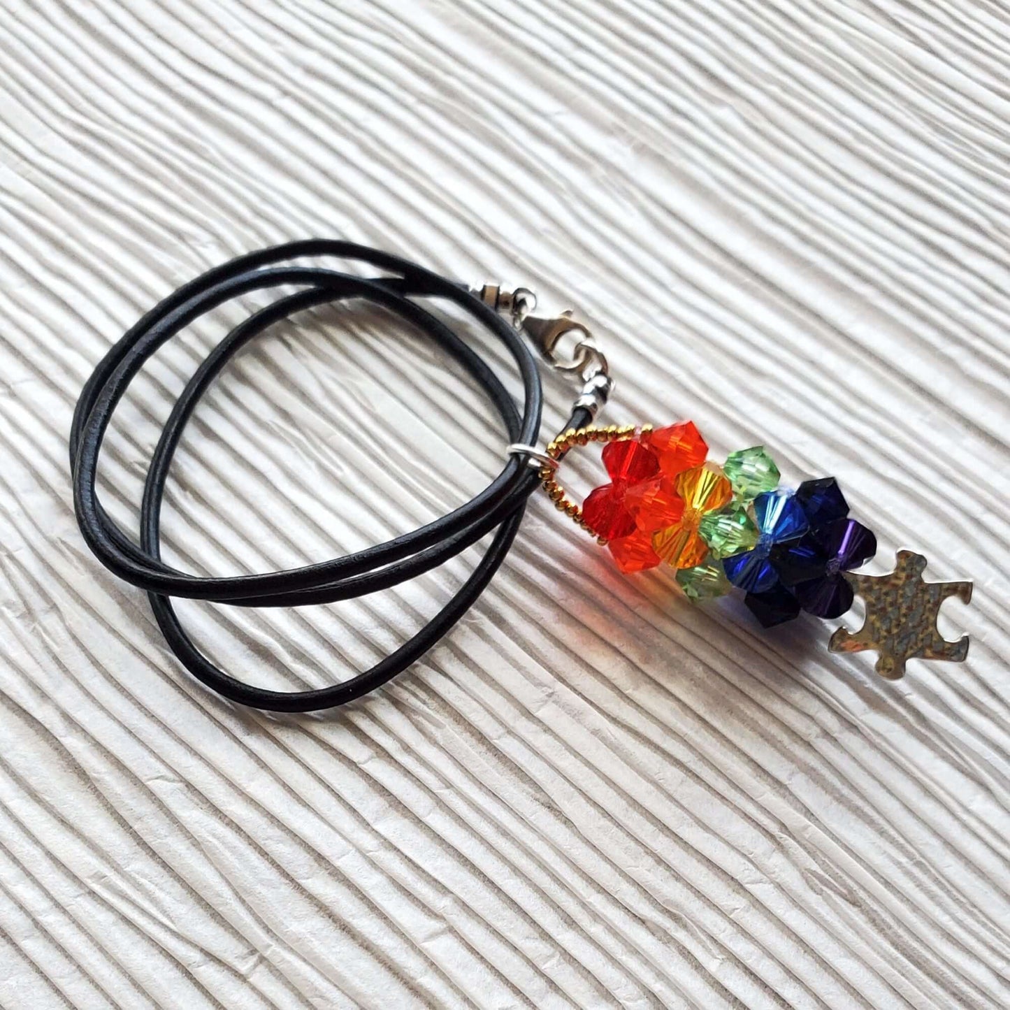 Necklace with colorful beads and autism charm on a textured white surface