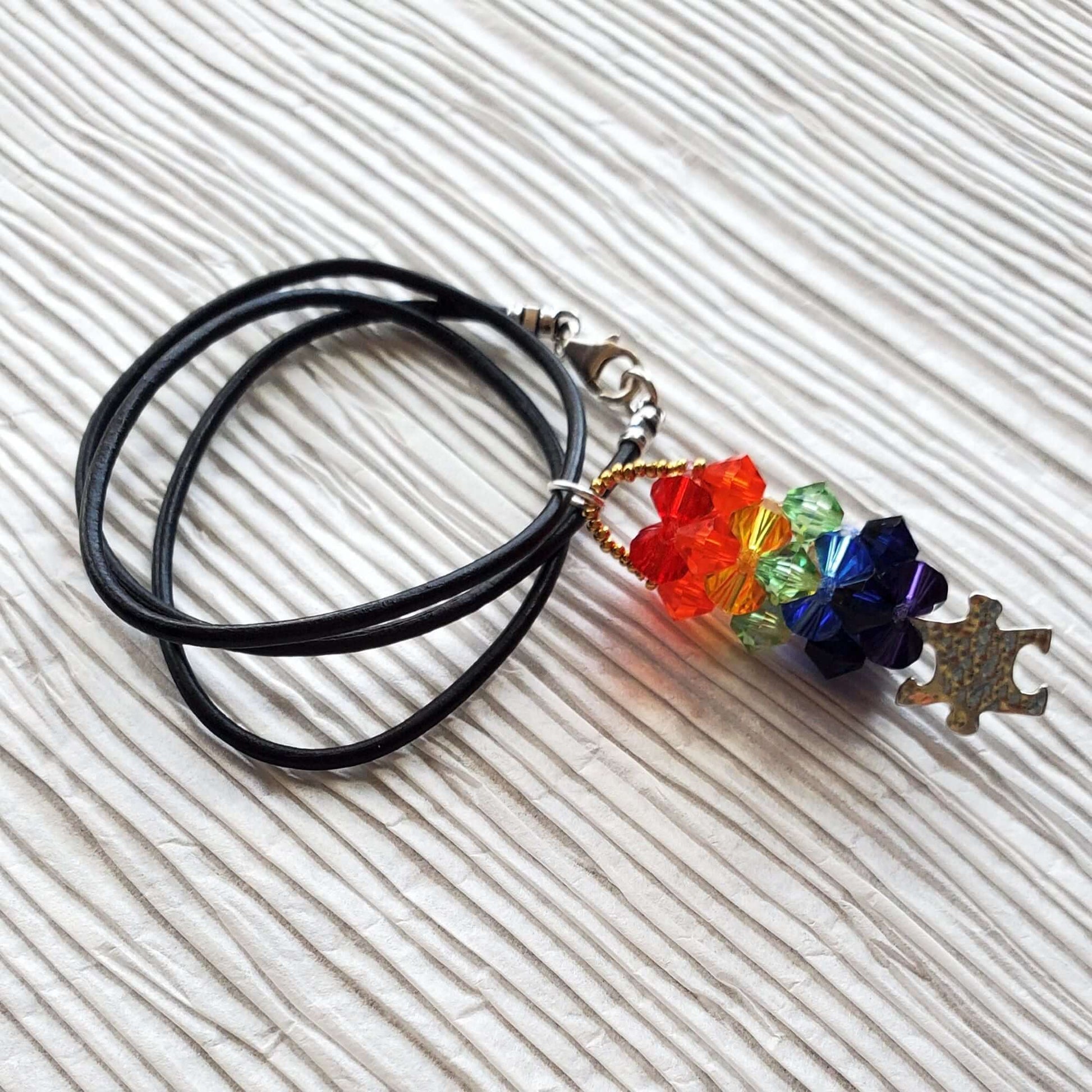 Necklace with colorful beads and autism charm on a textured white surface