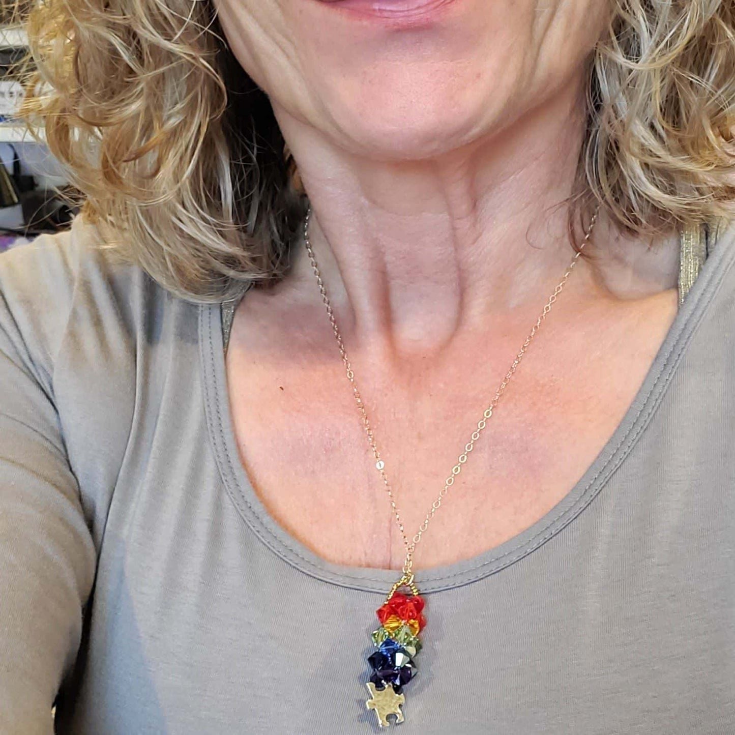 Woman wearing a necklace with colorful autism pendant
