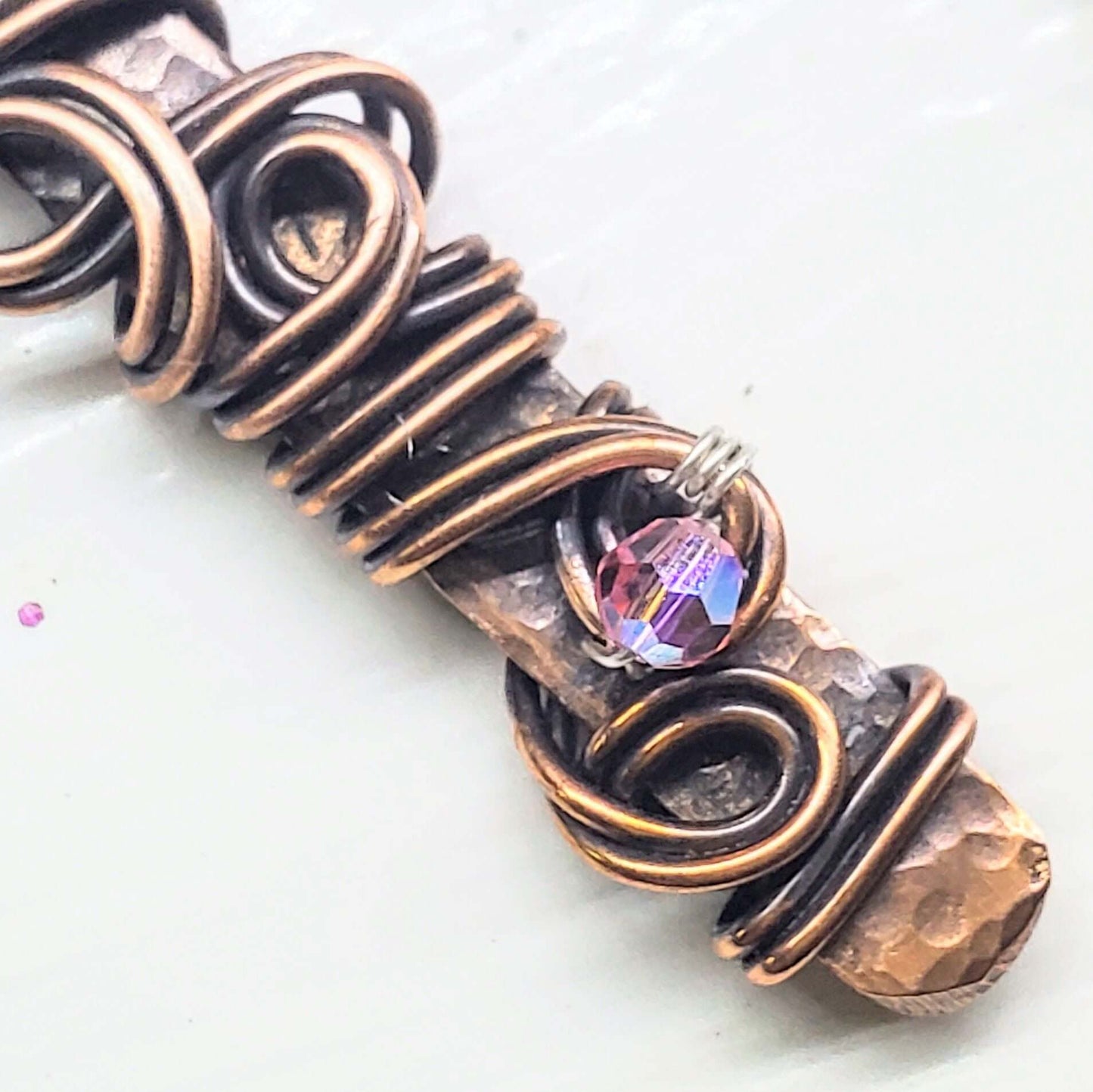Close-up of a copper bracelet with a pink gemstone on a white background