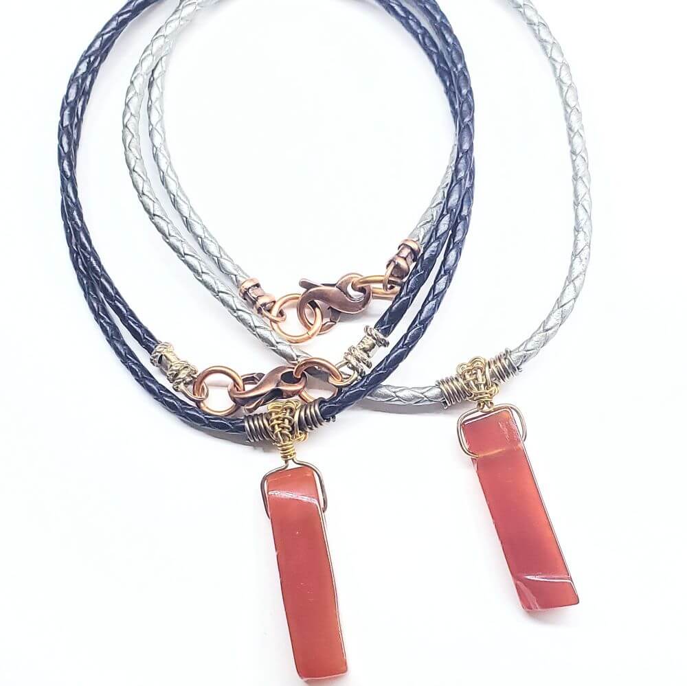Necklace with pink stone pendants on braided cords against a white background