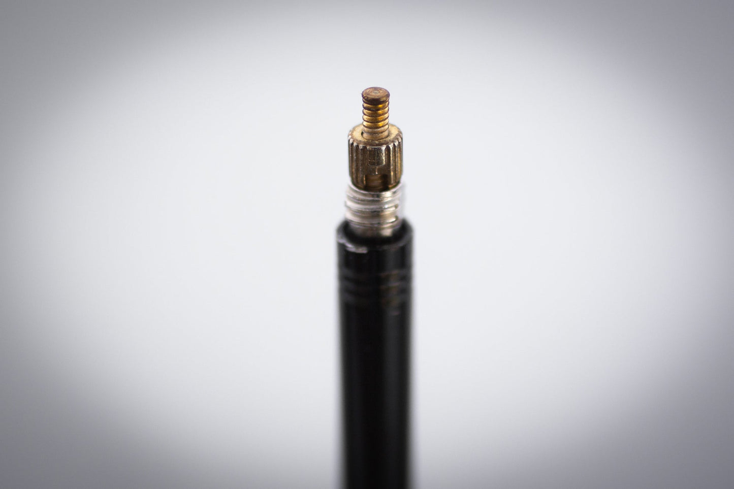 Tire pressure gauge with black hose and brass fitting on a gradient gray background