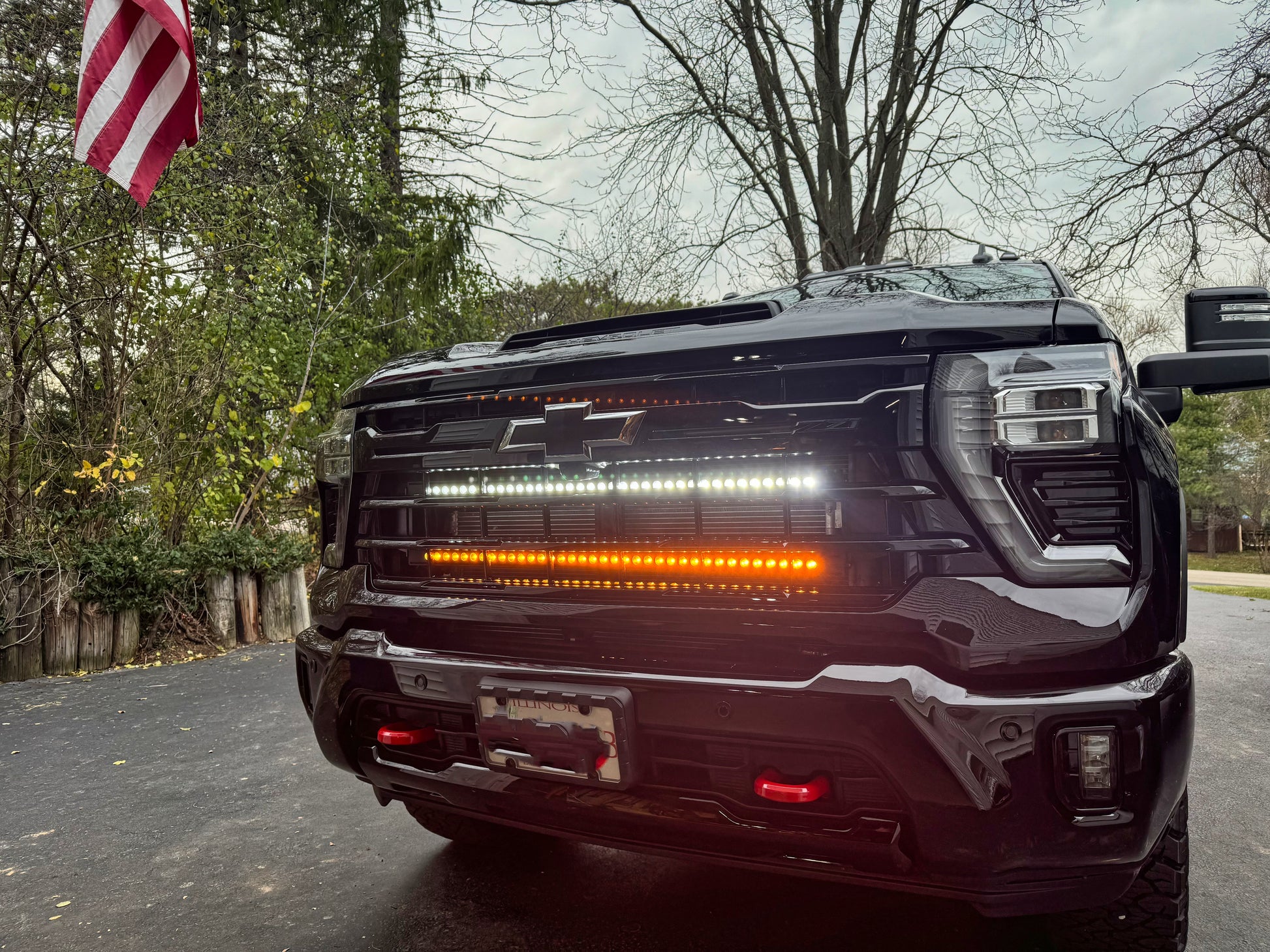 Back view of a black truck with LED lights on a street, American flag in the background.