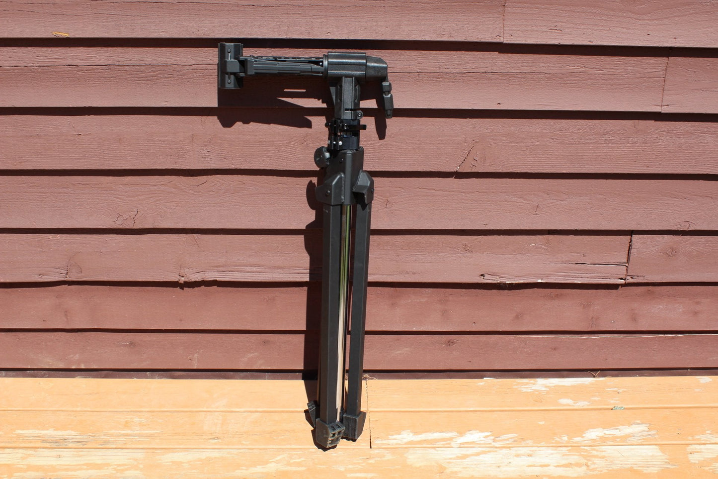 Black tripod against a wooden wall