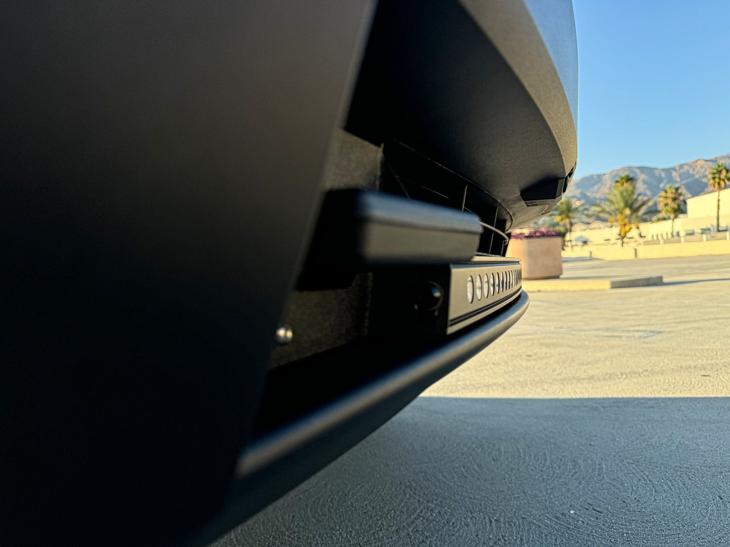 Close-up of a car's rear bumper with a scenic background