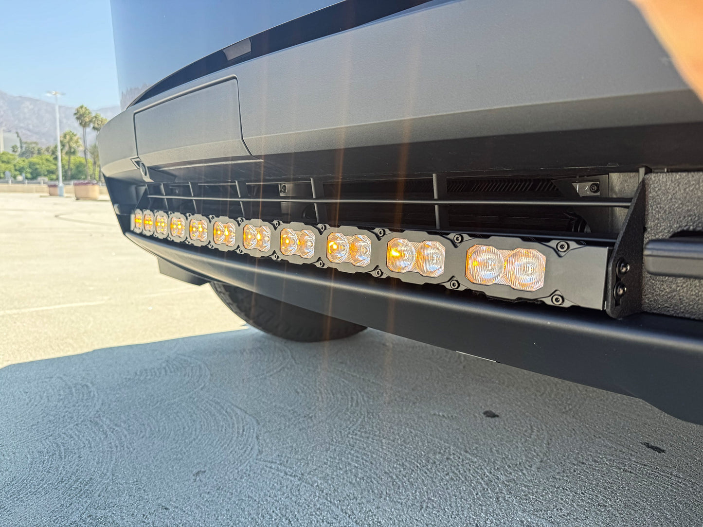 Close-up of a tesla's front bumper with LED lights on a clear day.